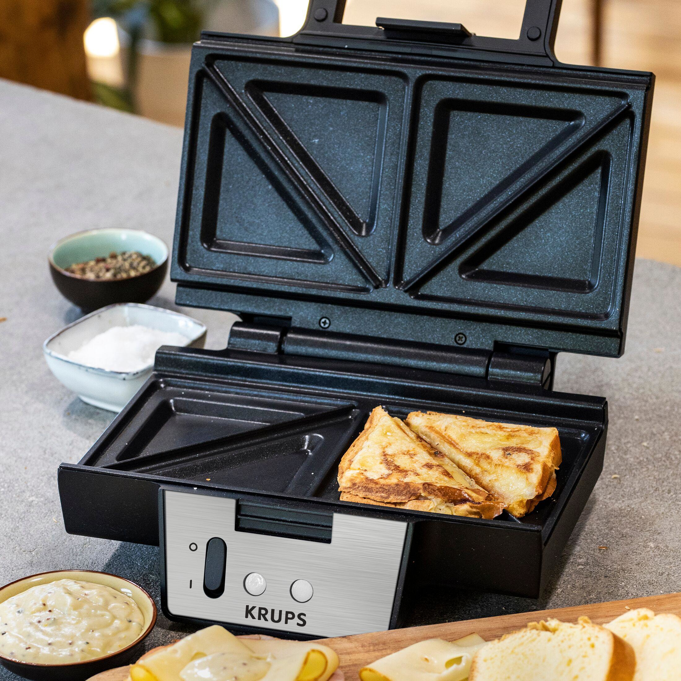 Un tostapane aperto con sandwich dorati, formaggio e salse.