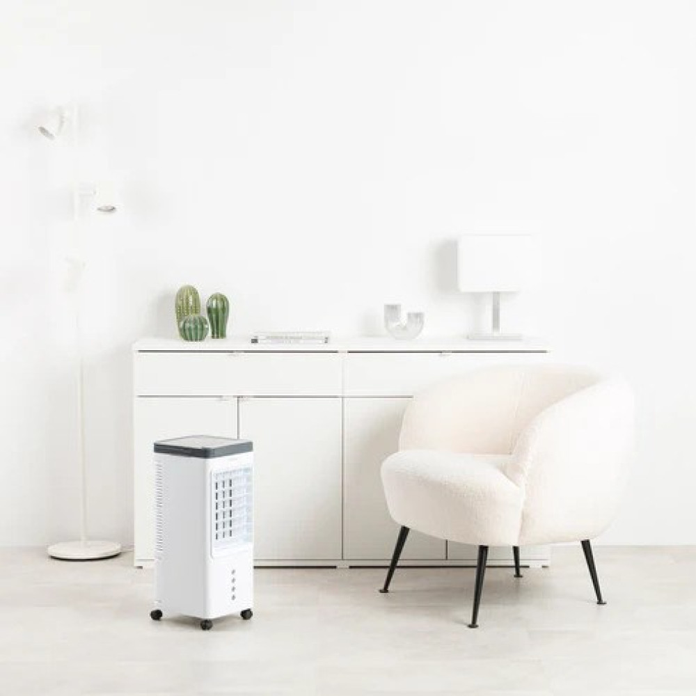 Un refrigeratore d'aria bianco si trova accanto a una poltrona bianca davanti a un mobile bianco.