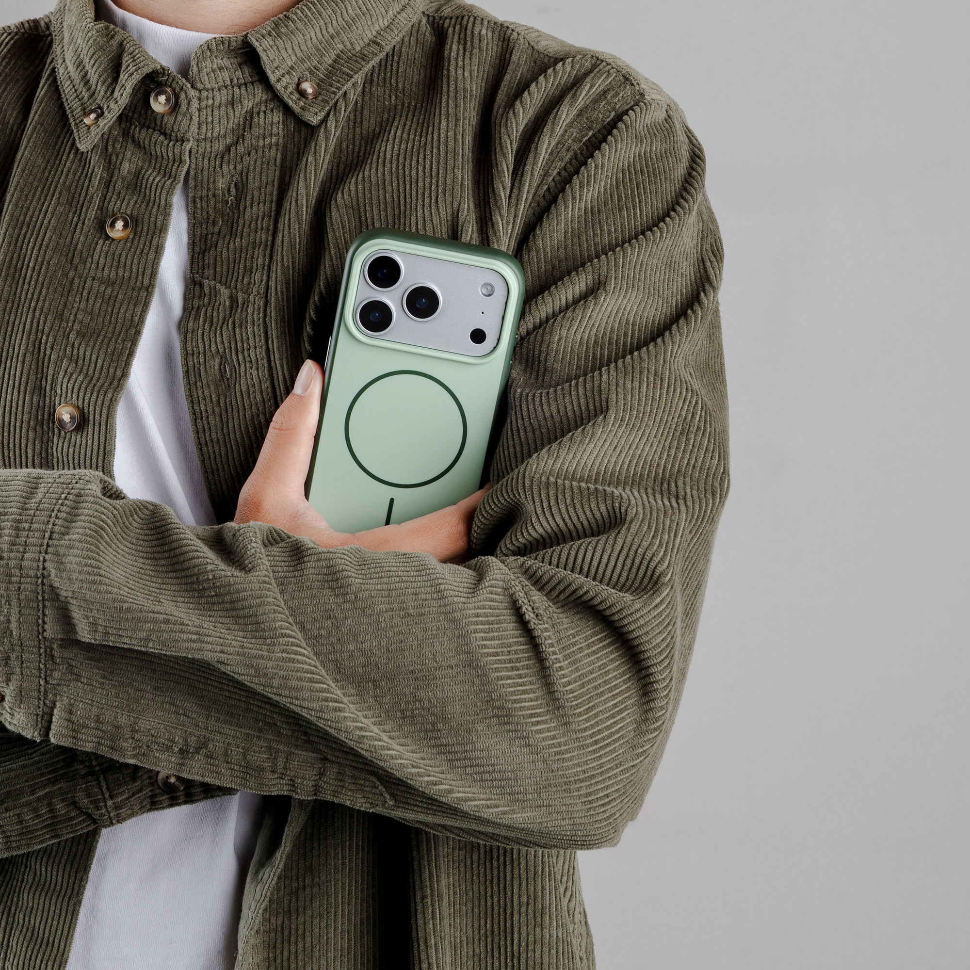 Persoon met lichtgroene telefoonhoes, draagt olijfgroene corduroy jas.