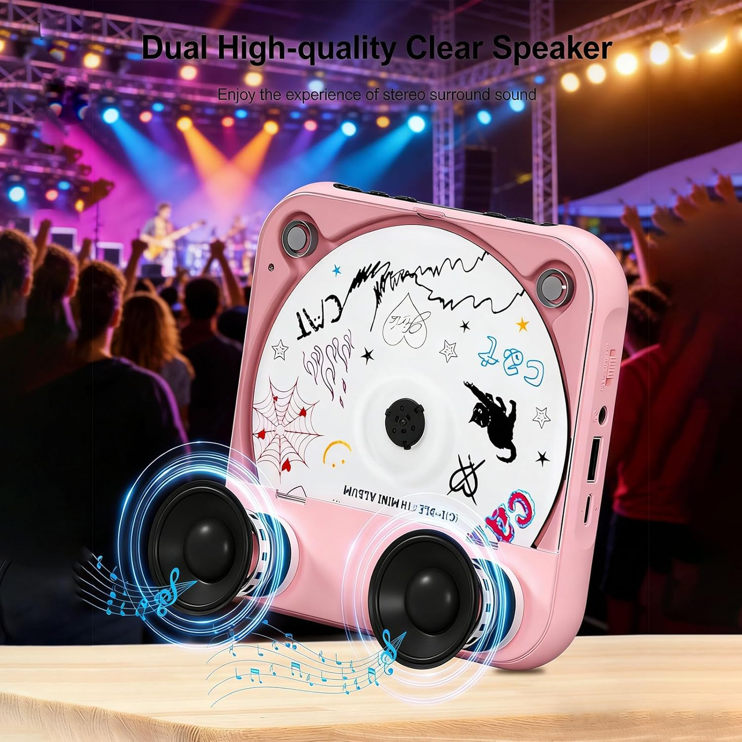 Rosa CD-Player mit zwei Lautsprechern vor einer Konzertbühne mit Publikum.