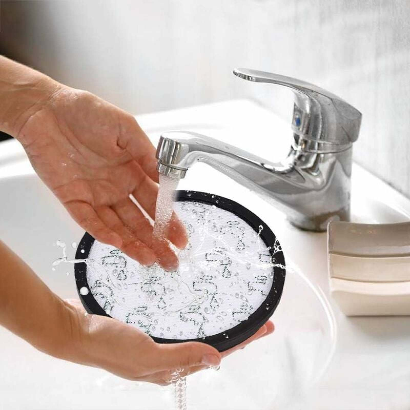 Hände halten einen runden Filter unter fließendem Wasser im Waschbecken.