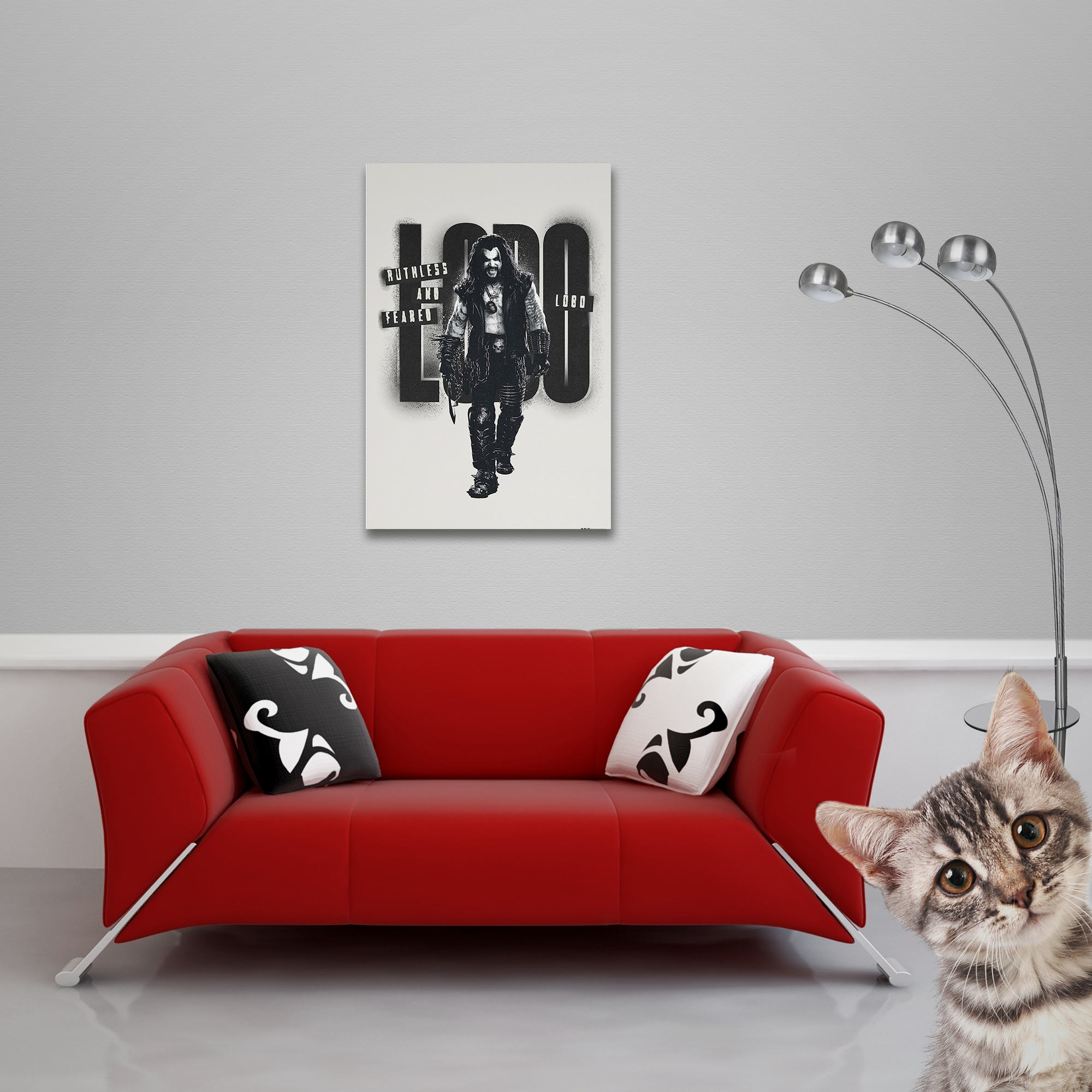 Ein rotes Sofa mit Kissen und einem Lobo-Poster an der Wand. Eine Katze lugt hervor.