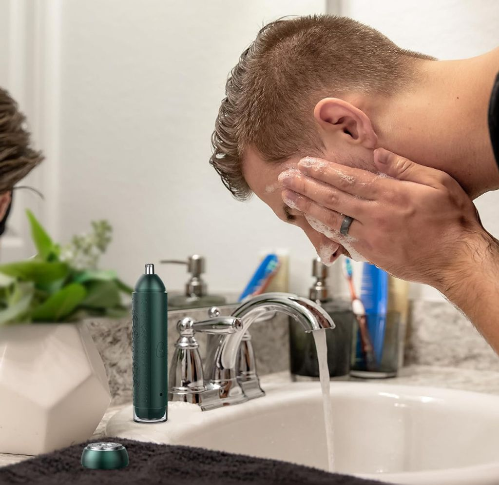 Mann wäscht sich im Waschbecken das Gesicht mit Schaum.