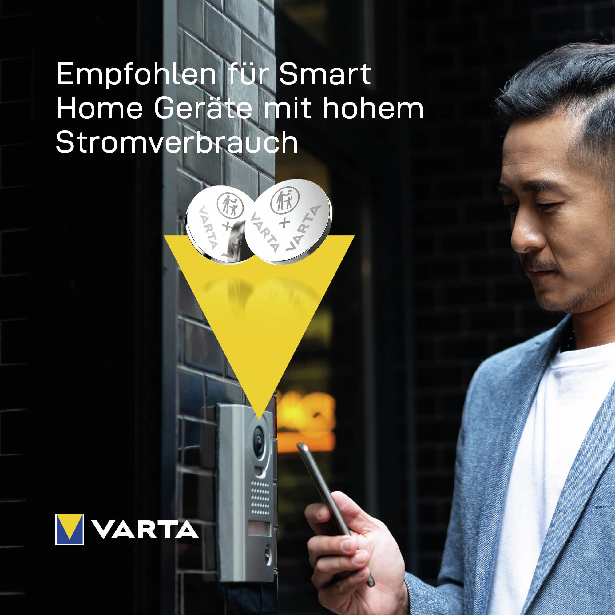 Mann hält Smartphone vor Varta-Batterien und eine Sprechanlage.
