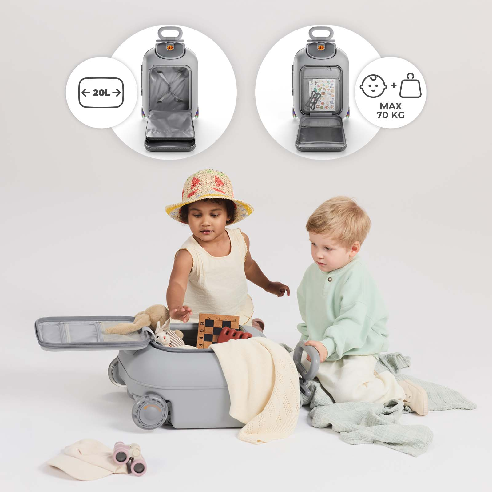 Zwei Kleinkinder spielen mit einem grauen Koffer, gefüllt mit Spielzeug und Decken.