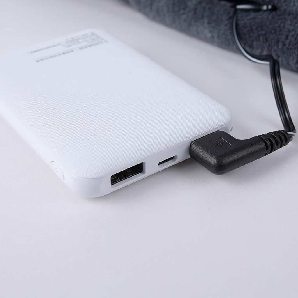 Eine weiße Powerbank mit einem schwarzen Kabel, das an der Seite eingesteckt ist.