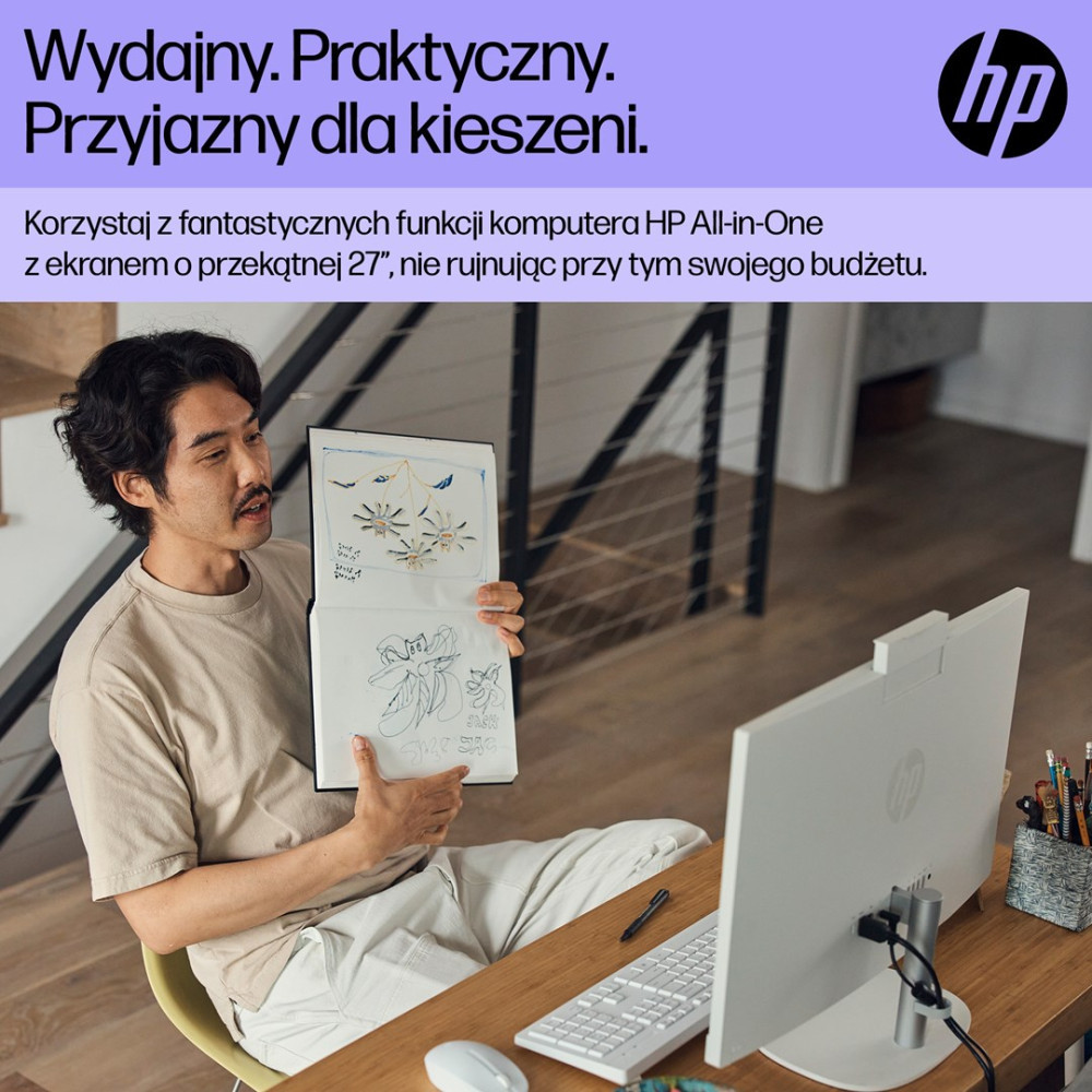 Mężczyzna trzyma szkicownik przed komputerem HP All-in-One.