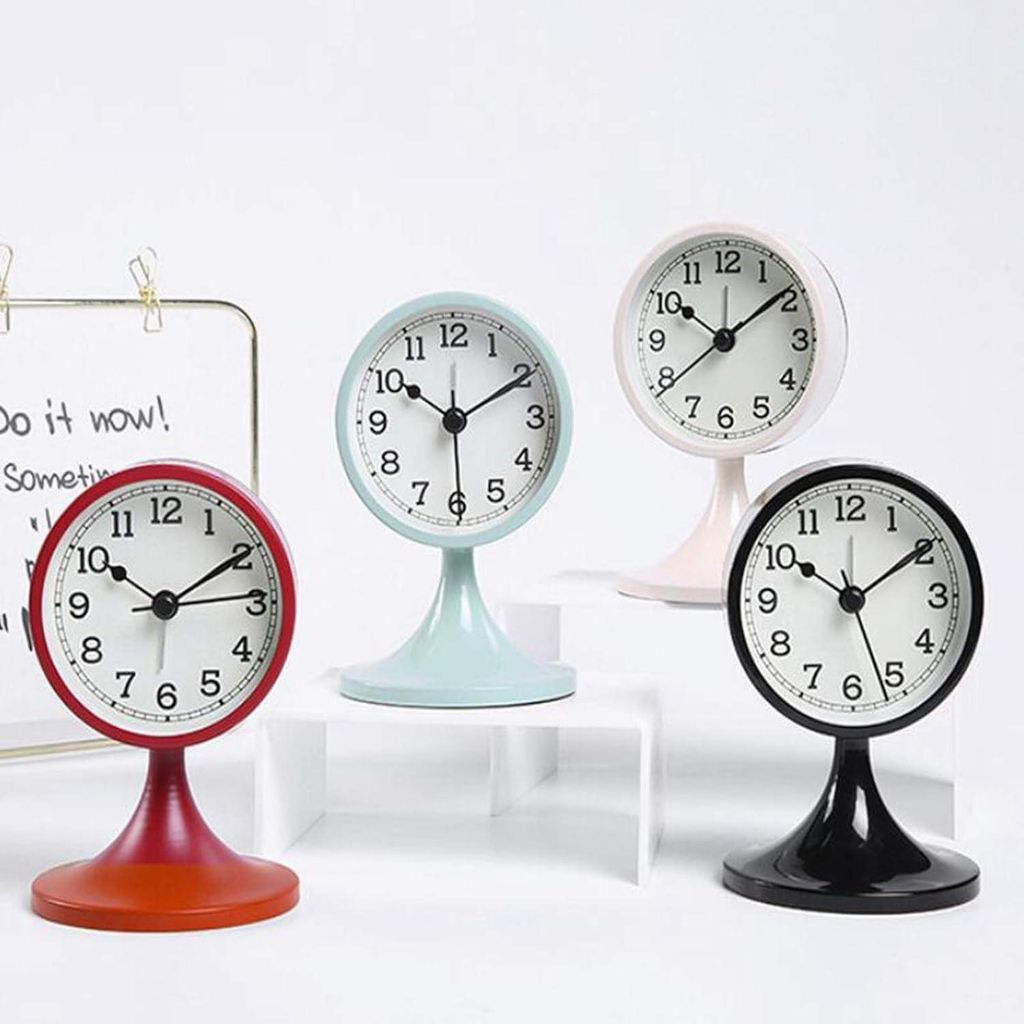 Vier Vintage-Wecker in Rot, Blau, Rosa und Schwarz auf weißen Ständern.