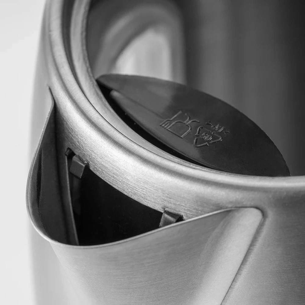 Zbliżenie metalowej pokrywy czajnika z czarną plastikową wkładką.
