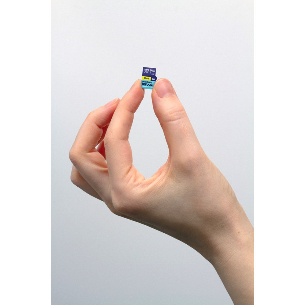 Dłoń trzyma dwie maleńkie karty microSD na pierwszym planie. Biała ściana w tle.