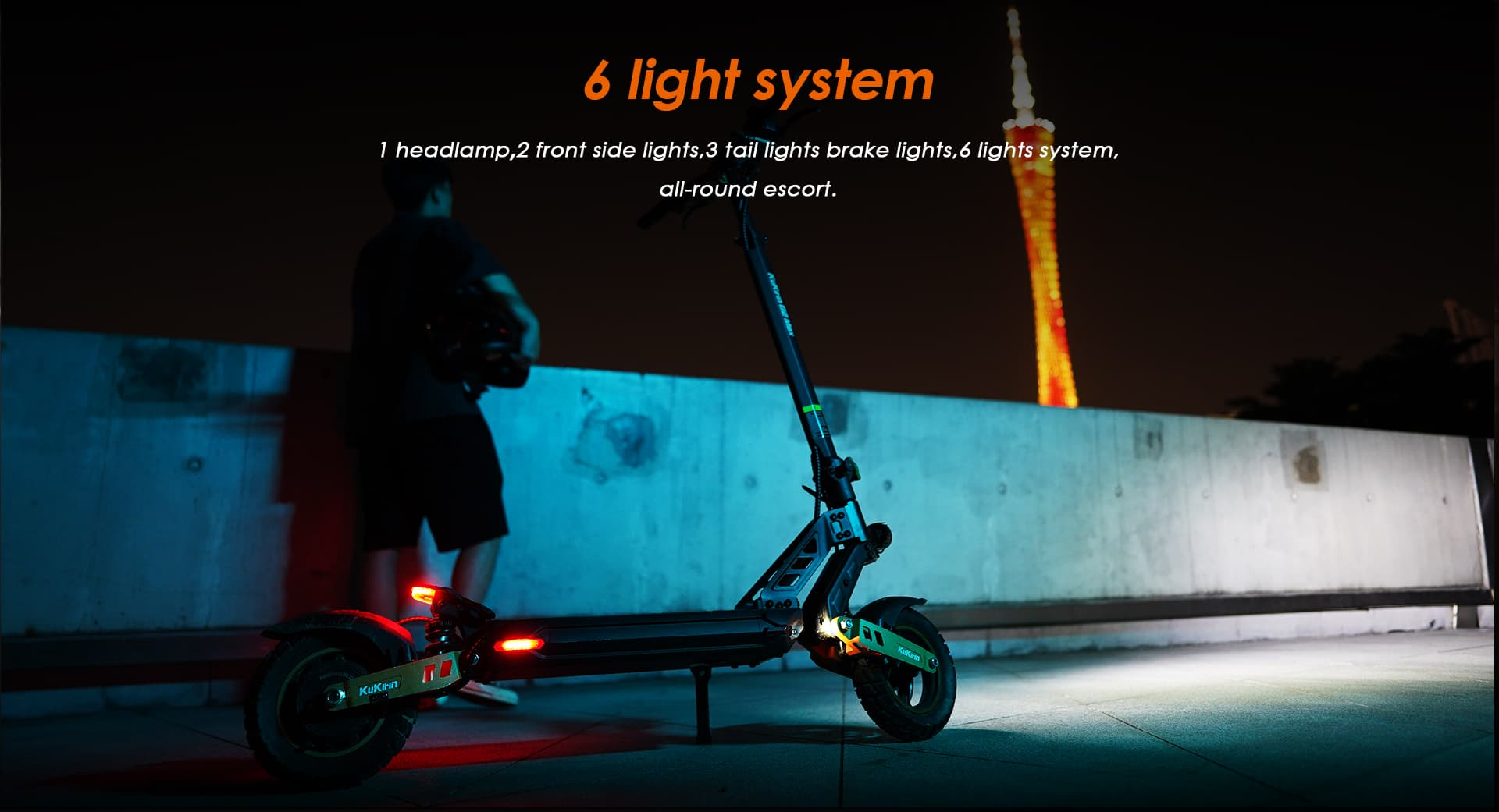 Un uomo accanto a uno scooter elettrico di notte, illuminato da luci. Una torre è visibile sullo sfondo.