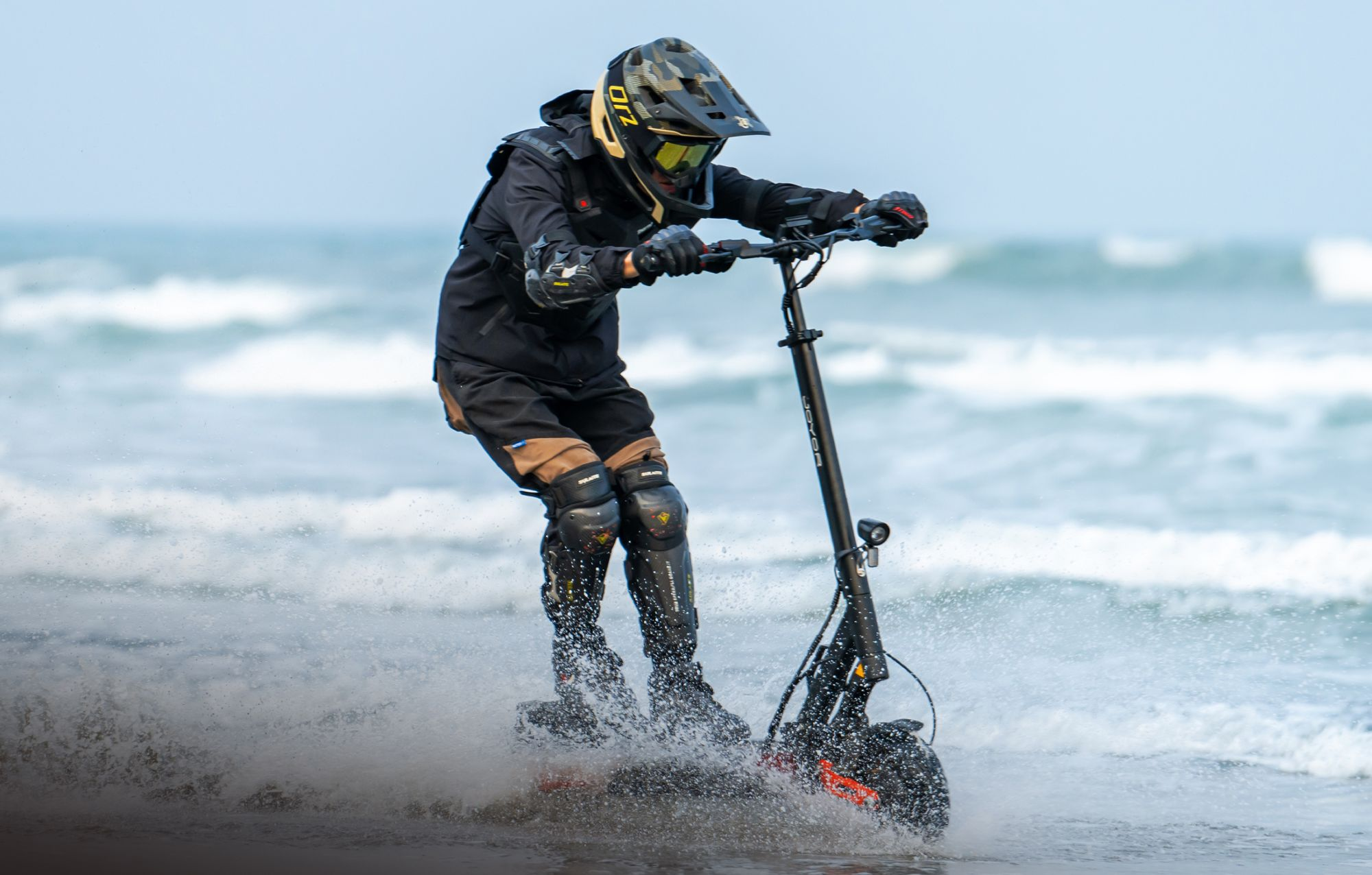 Persona in abiti protettivi guida uno scooter elettrico attraverso l'acqua bassa del mare.