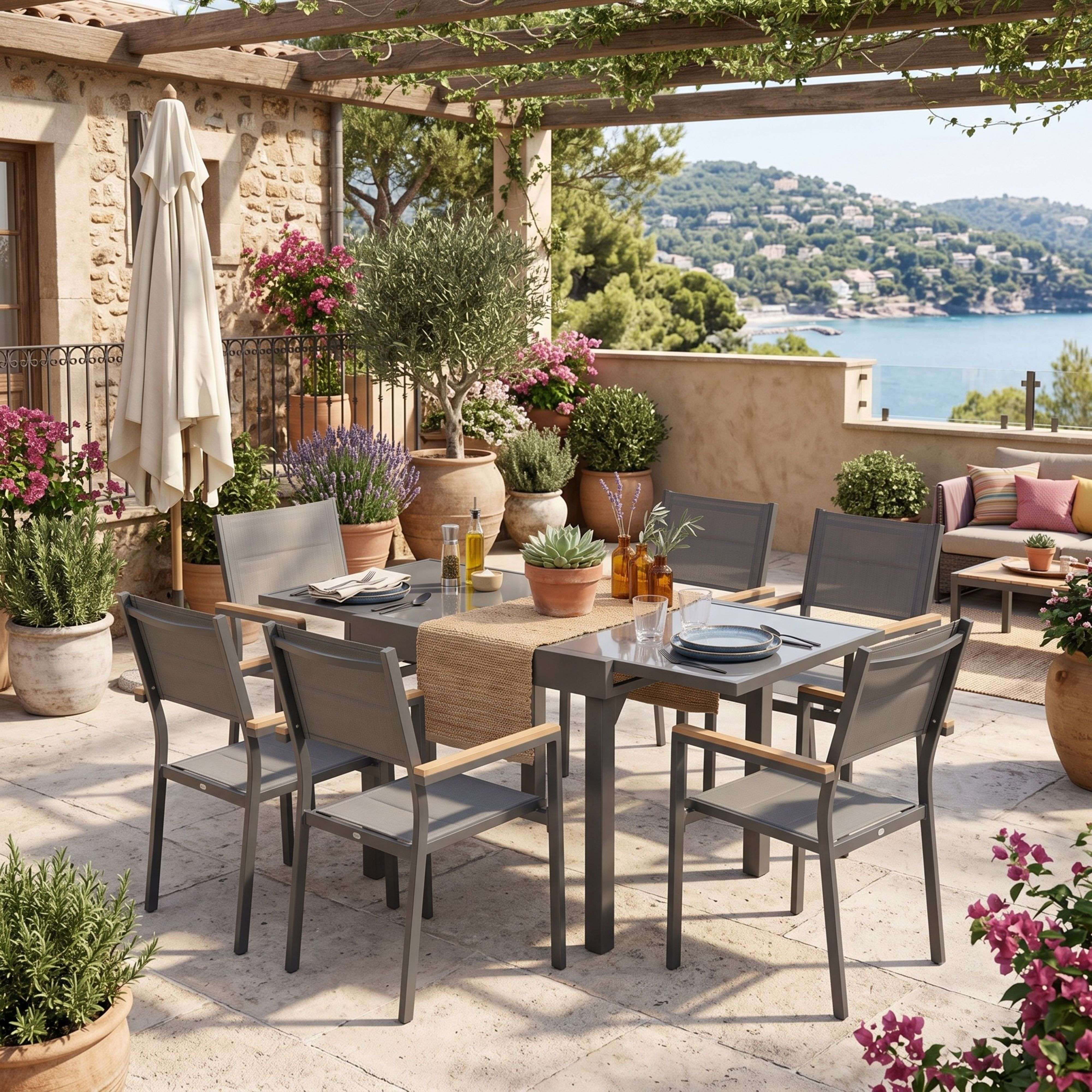 Una mesa de comedor con seis sillas en un patio con vistas al mar, rodeada de plantas.