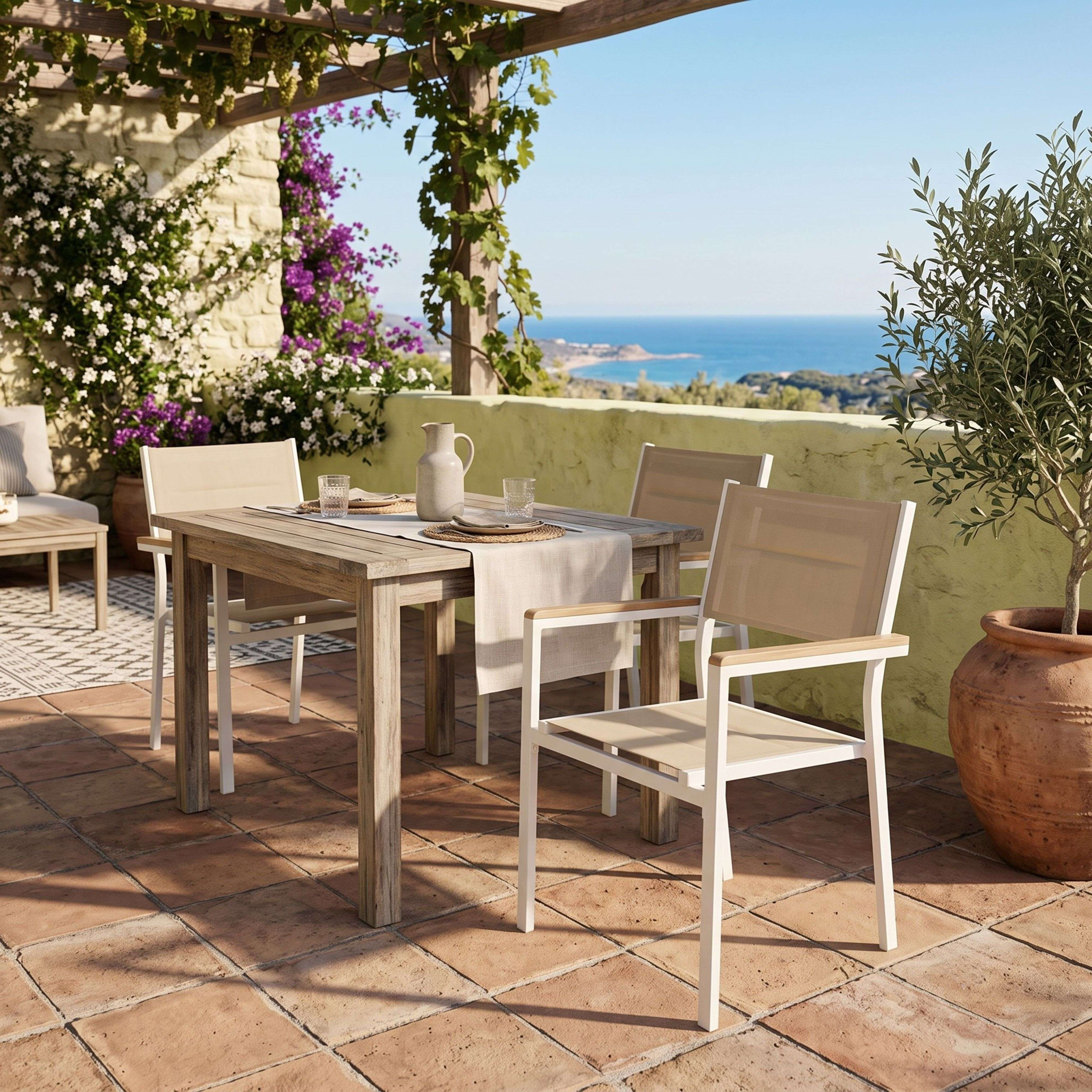 Patio con mesa, sillas y vista al mar, bajo una pérgola con vides.
