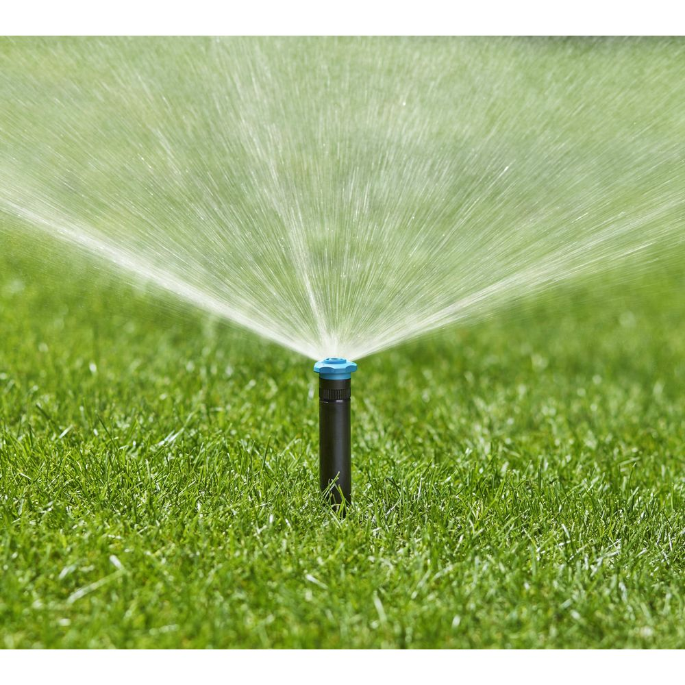 Ein Sprinkler bewässert einen grünen Rasen mit feinen Wasserstrahlen.