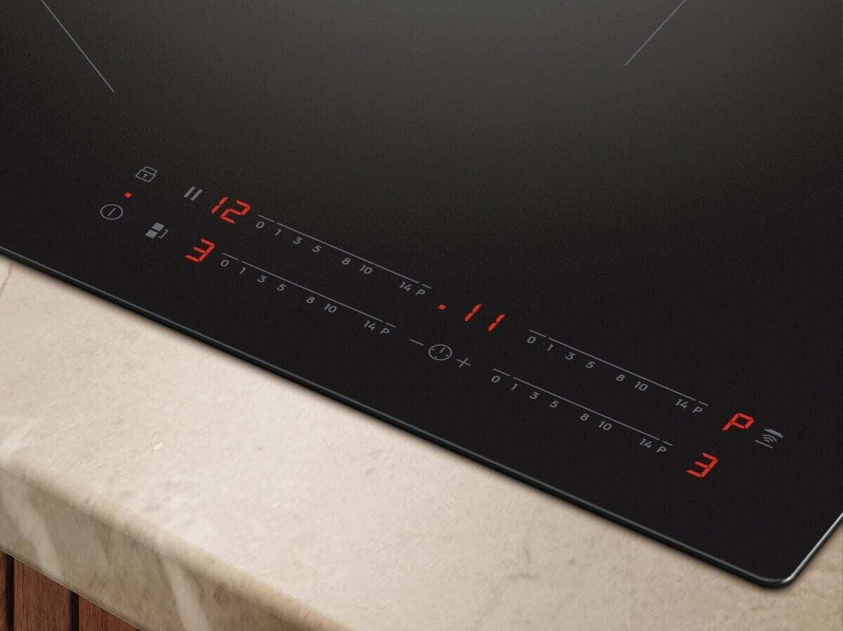 Piano cottura a induzione nero con display digitali rossi per potenza e timer.