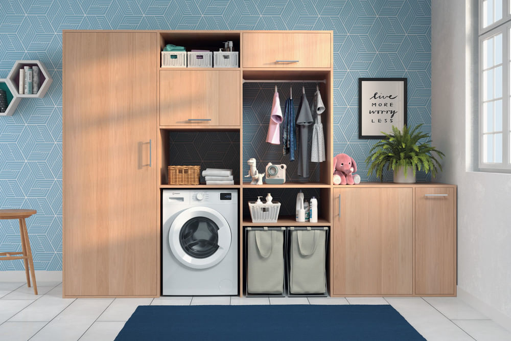 Lavanderia moderna con mobili in legno, lavatrice e vestiti appesi.