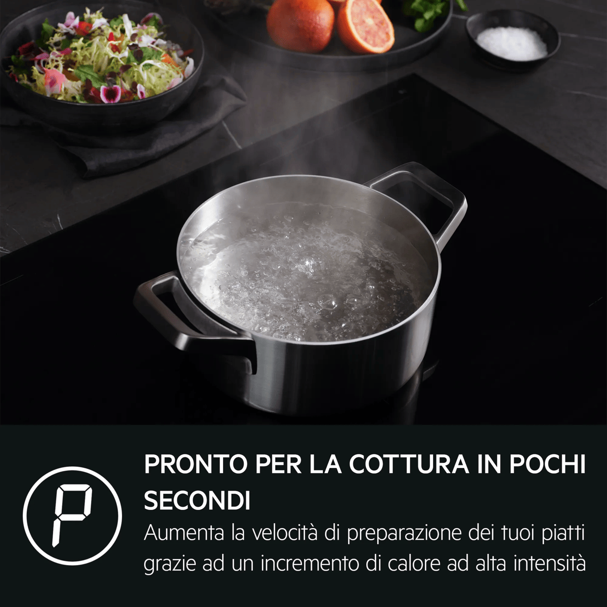 Una olla de agua hirviendo en una placa de inducción, junto a una ensalada y naranjas.