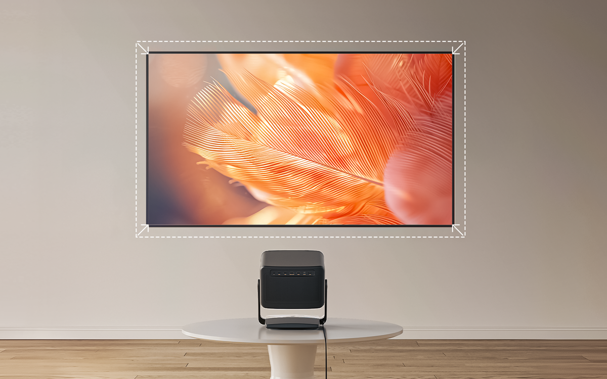Un proiettore nero su un tavolo bianco di fronte a un grande TV che mostra l'immagine di una piuma arancione.