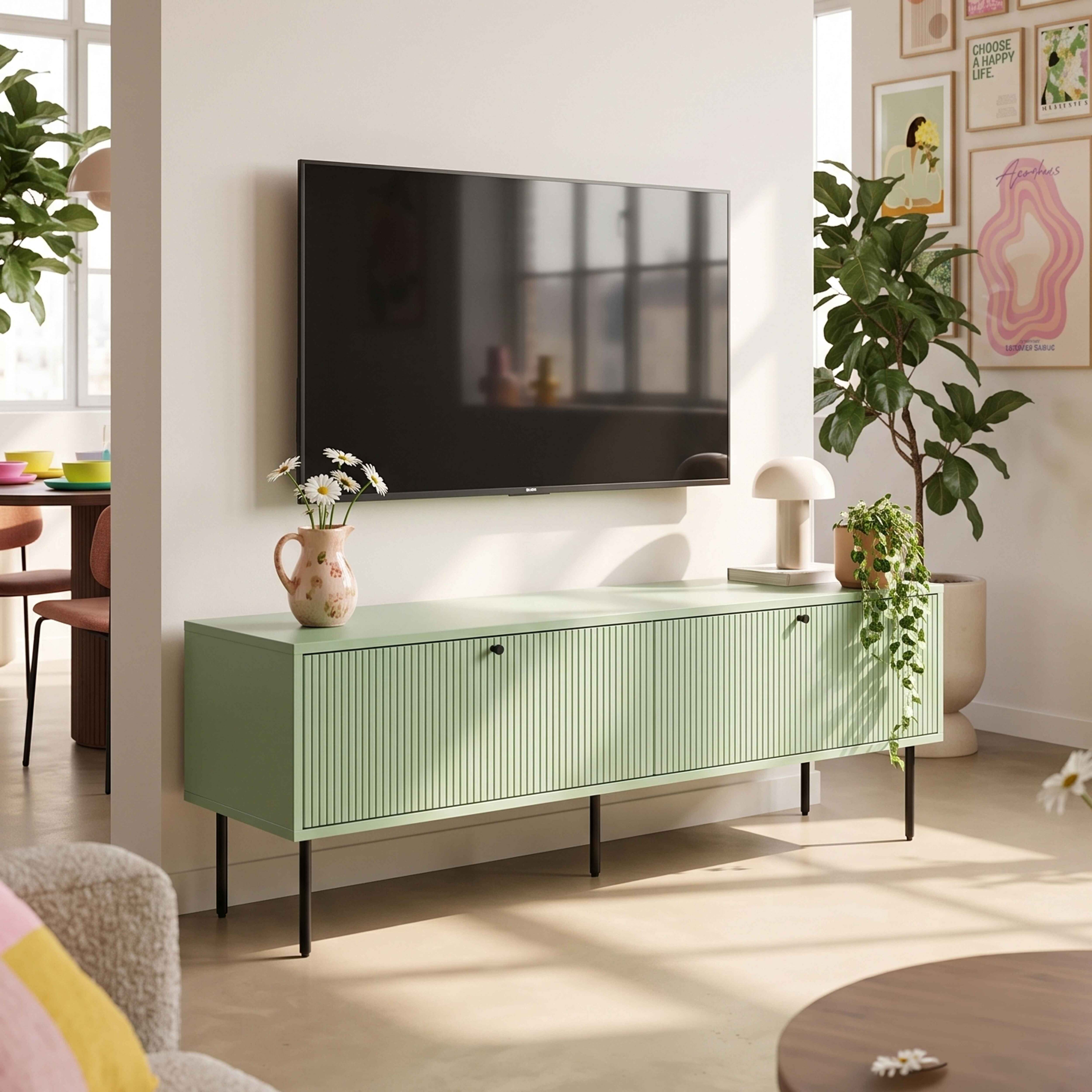 Ein grünes Sideboard mit Fernseher, Lampe und Pflanzen in einem hellen Raum.