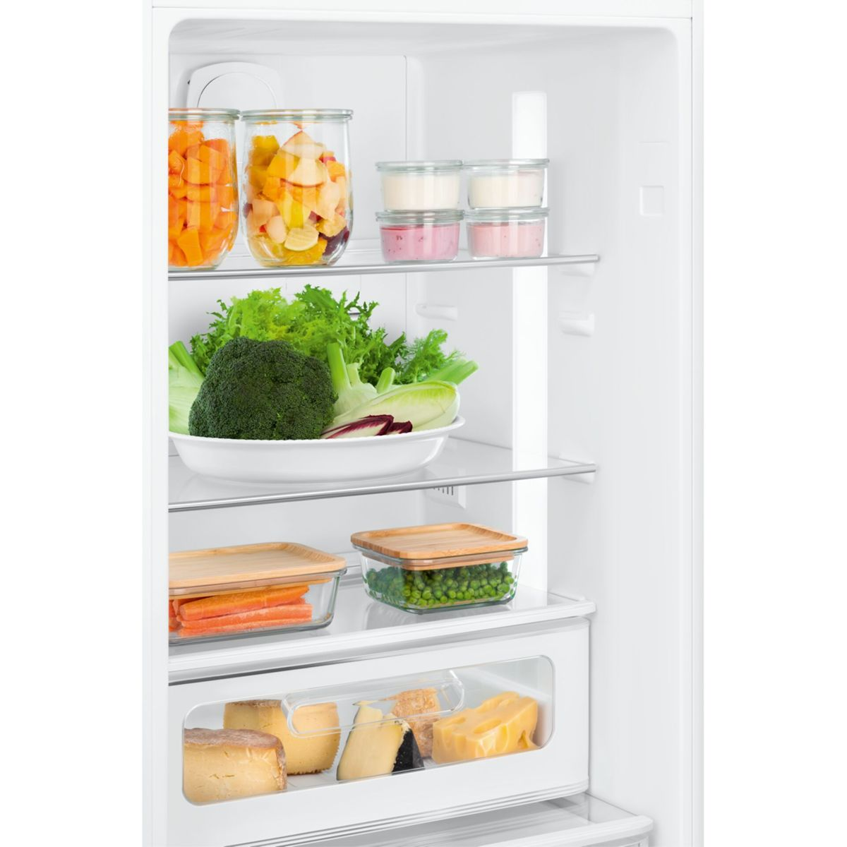 Un refrigerador abierto con comida en estantes: zanahorias, frutas, yogur, brócoli, guisantes y queso.