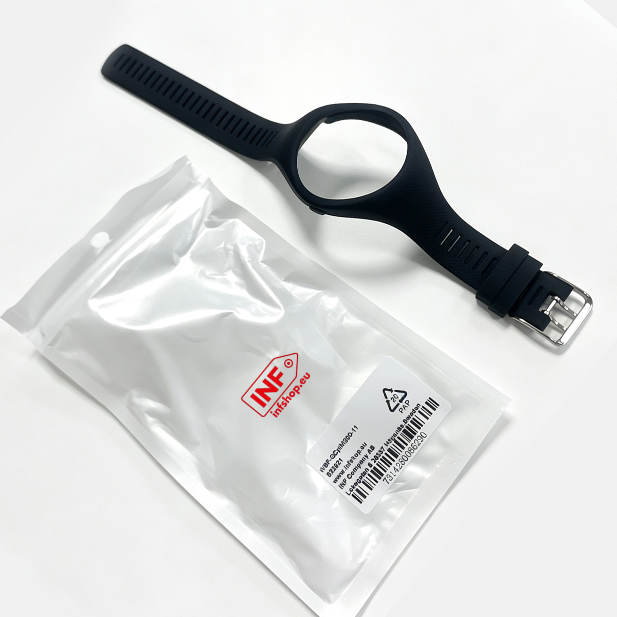 Ein schwarzes Uhrenarmband liegt neben einer durchsichtigen Verpackung mit Etikett.