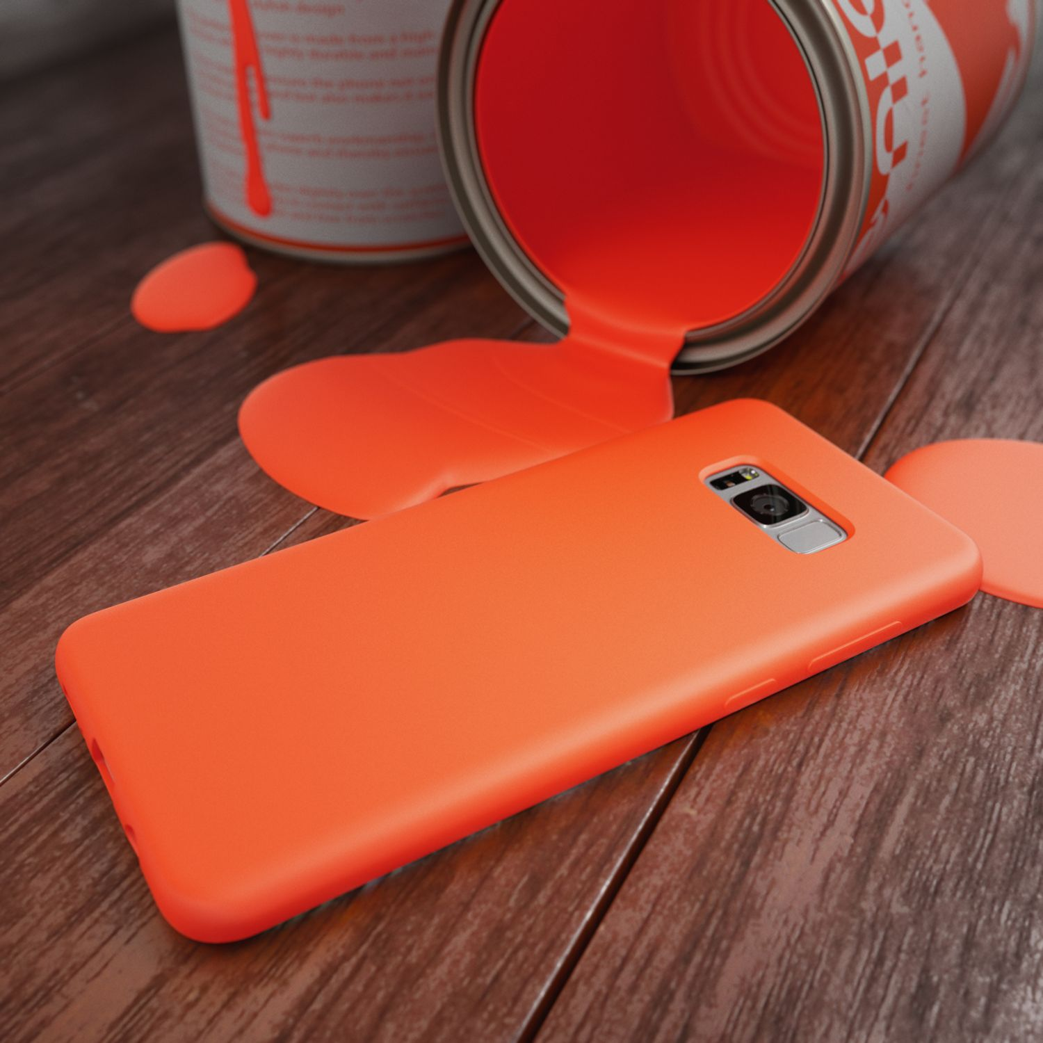 Ein Orangen-Handyhülle liegt neben einer umgekippten Farbdose mit verschütteter oranger Farbe.