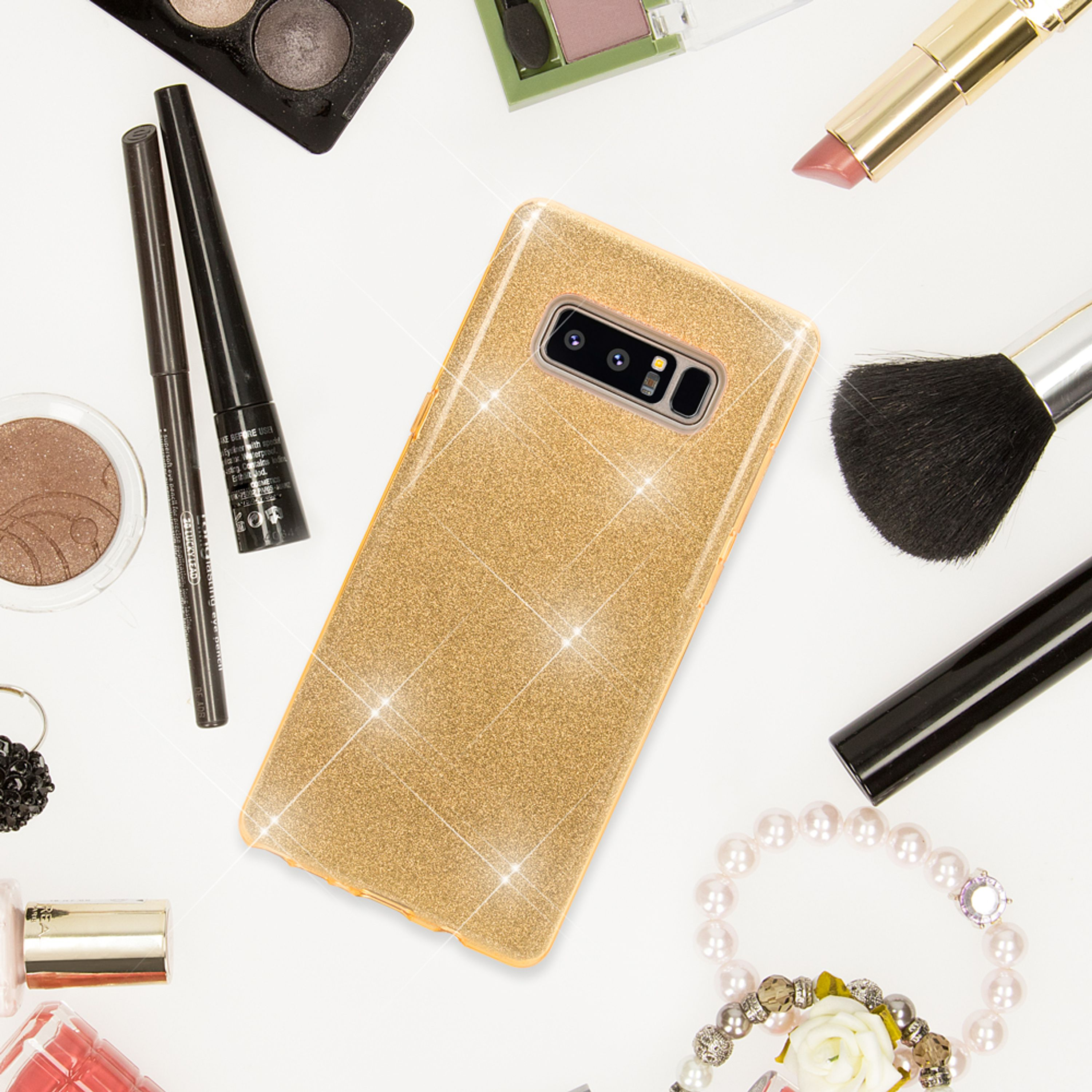 Goldenes Glitzer-Handyhülle umgeben von Make-up-Artikeln.