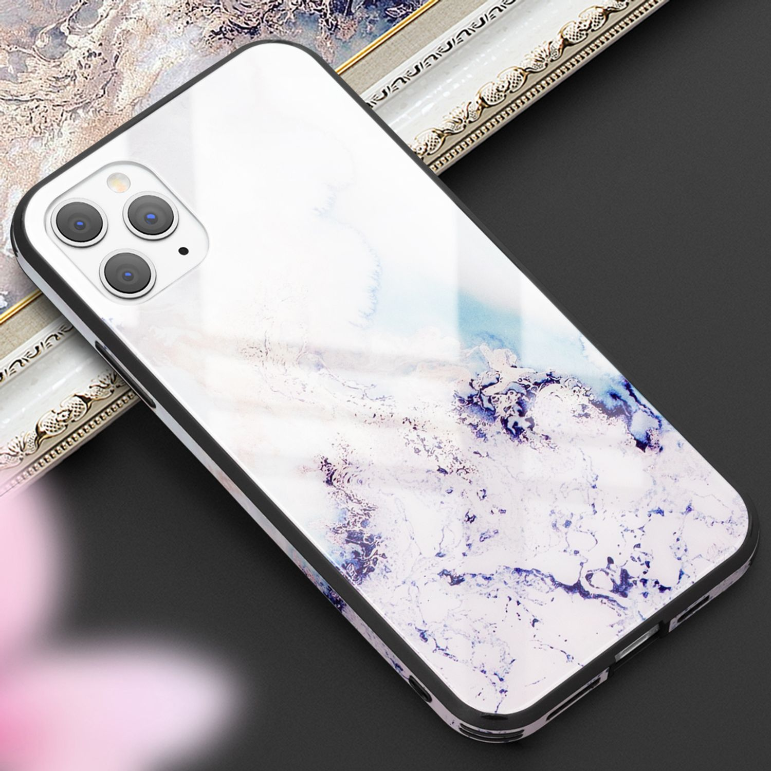 Ein Smartphone mit Marmormuster-Hülle liegt auf dunklem Untergrund.