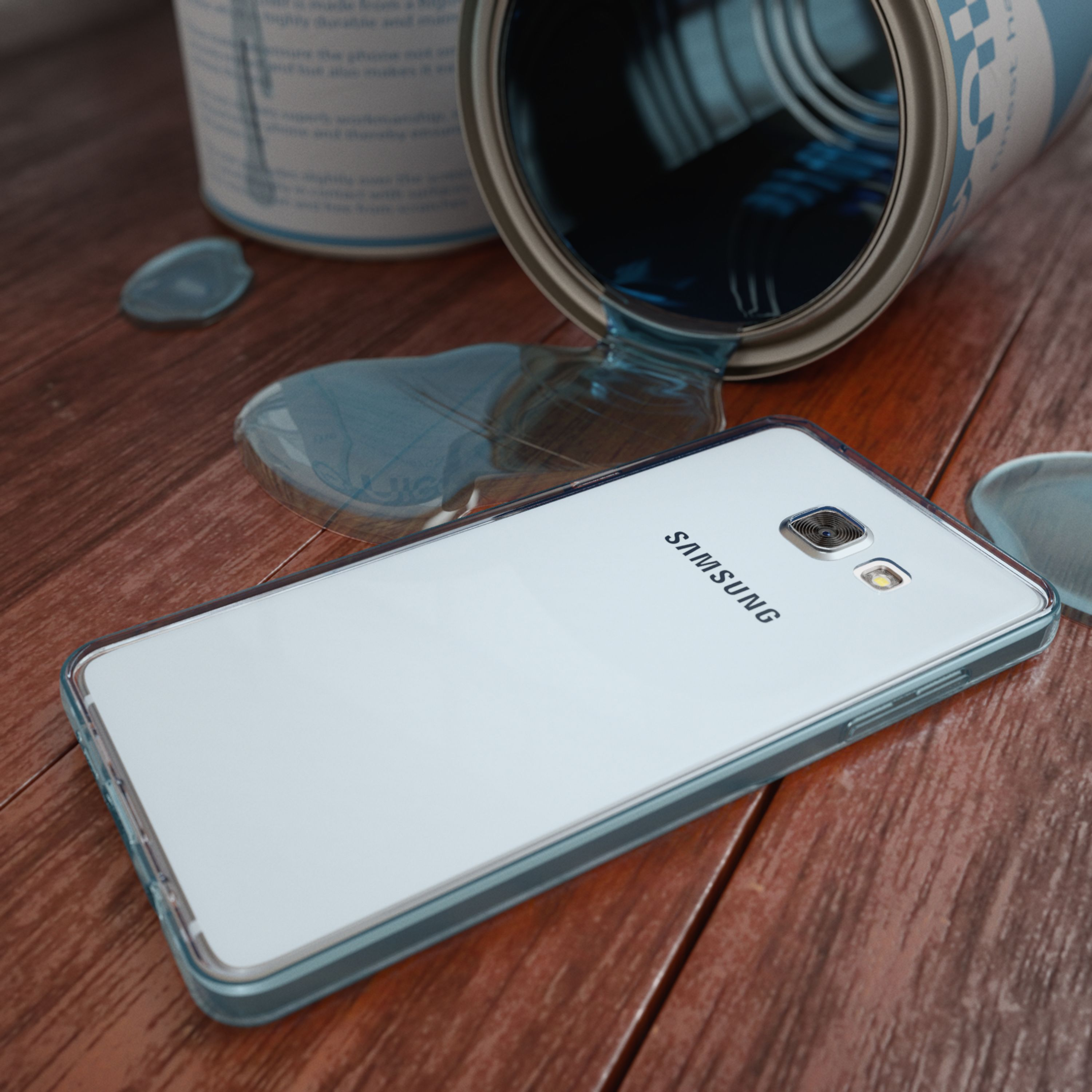 Ein umgekippter Farbeimer verschüttet blaue Farbe auf ein Smartphone auf einem Holztisch.