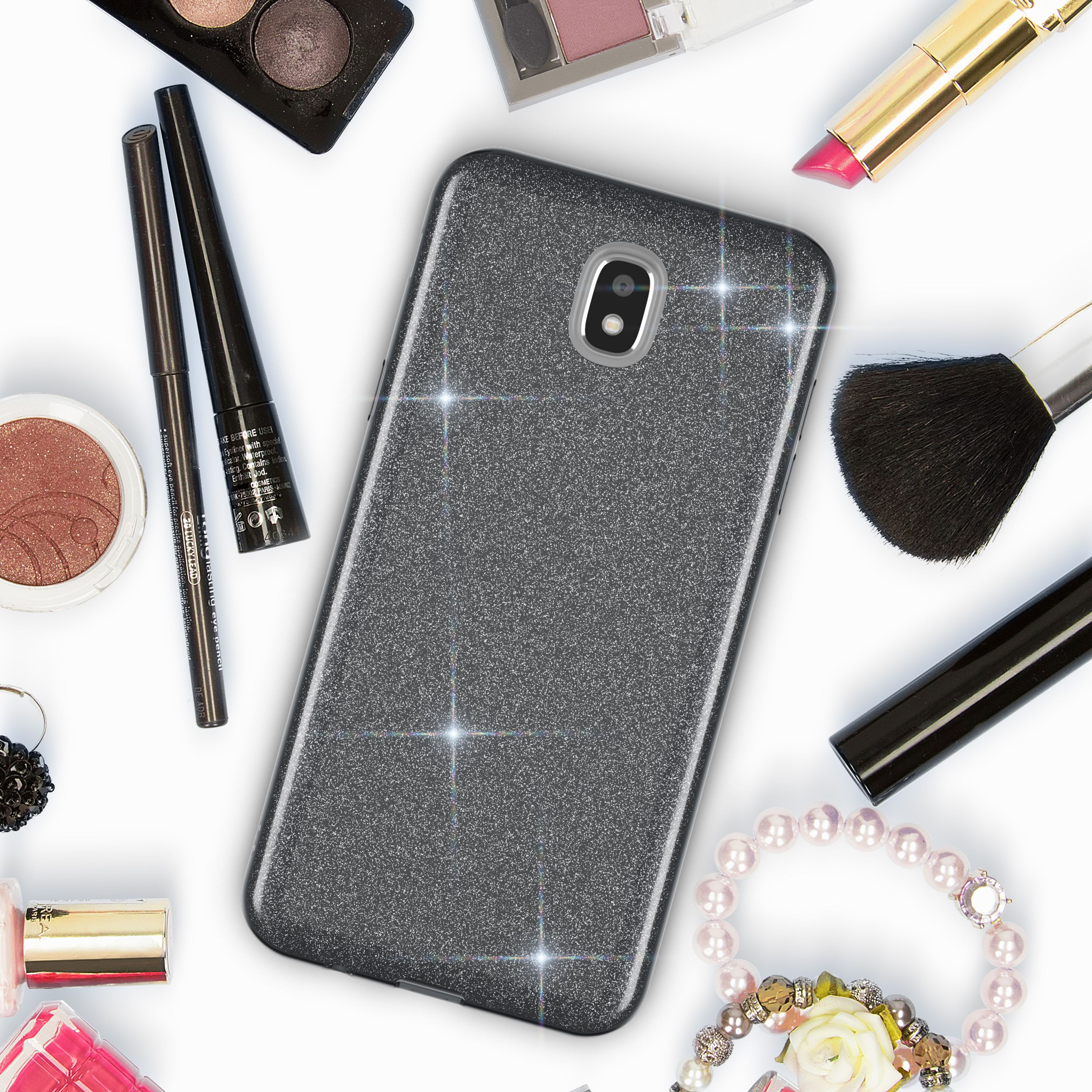 Graues Glitzer-Handyhülle umgeben von Make-up: Lidschatten, Lippenstift, Pinsel.