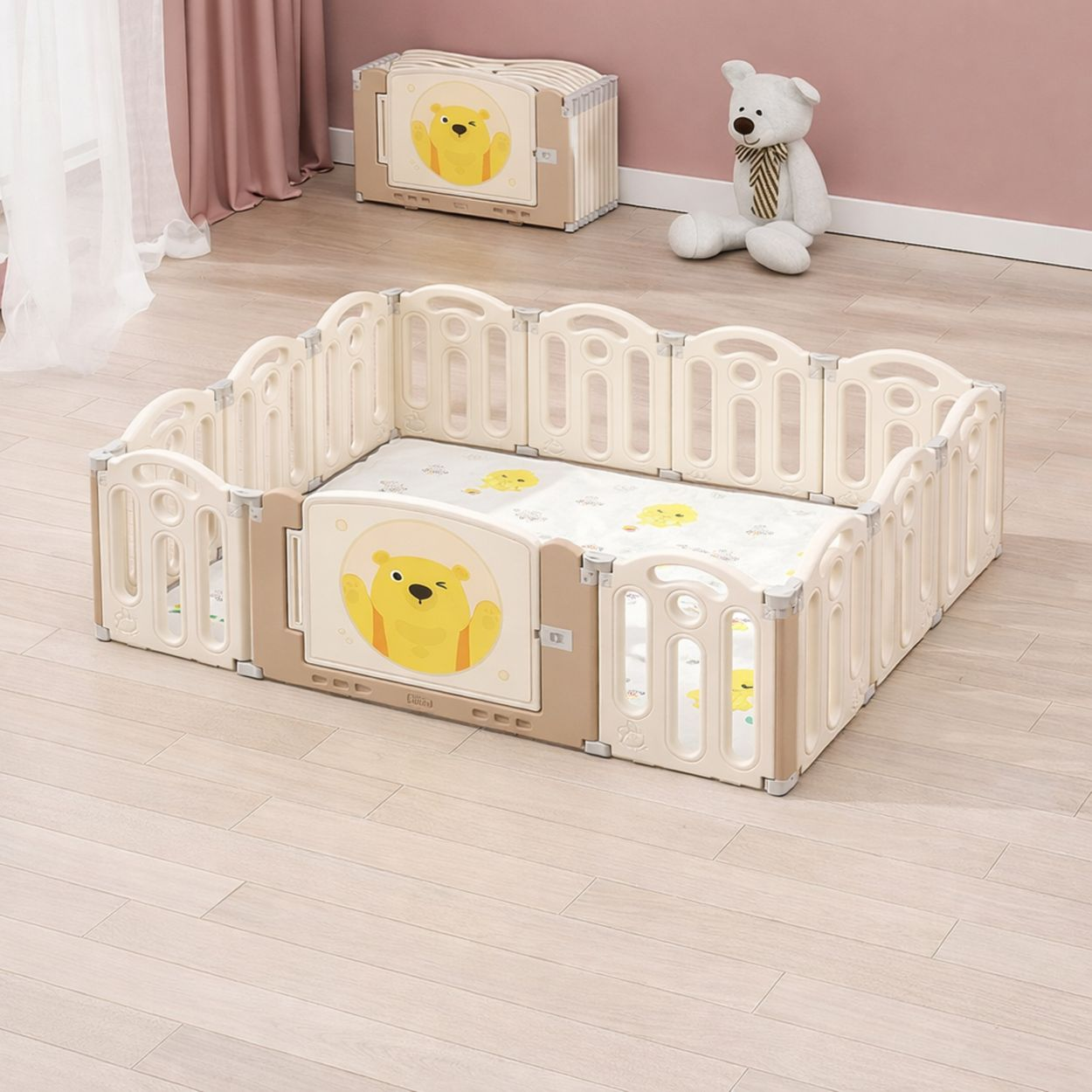 Ein beiger Laufstall mit Winnie-the-Pooh-Design steht auf Holzboden. Ein weißer Teddybär sitzt dahinter.