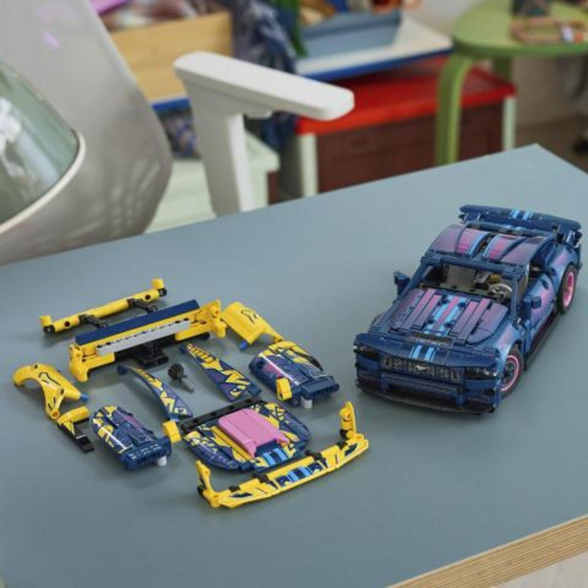Auto Lego blu e rosa parzialmente assemblata con pezzi gialli e blu sparsi.