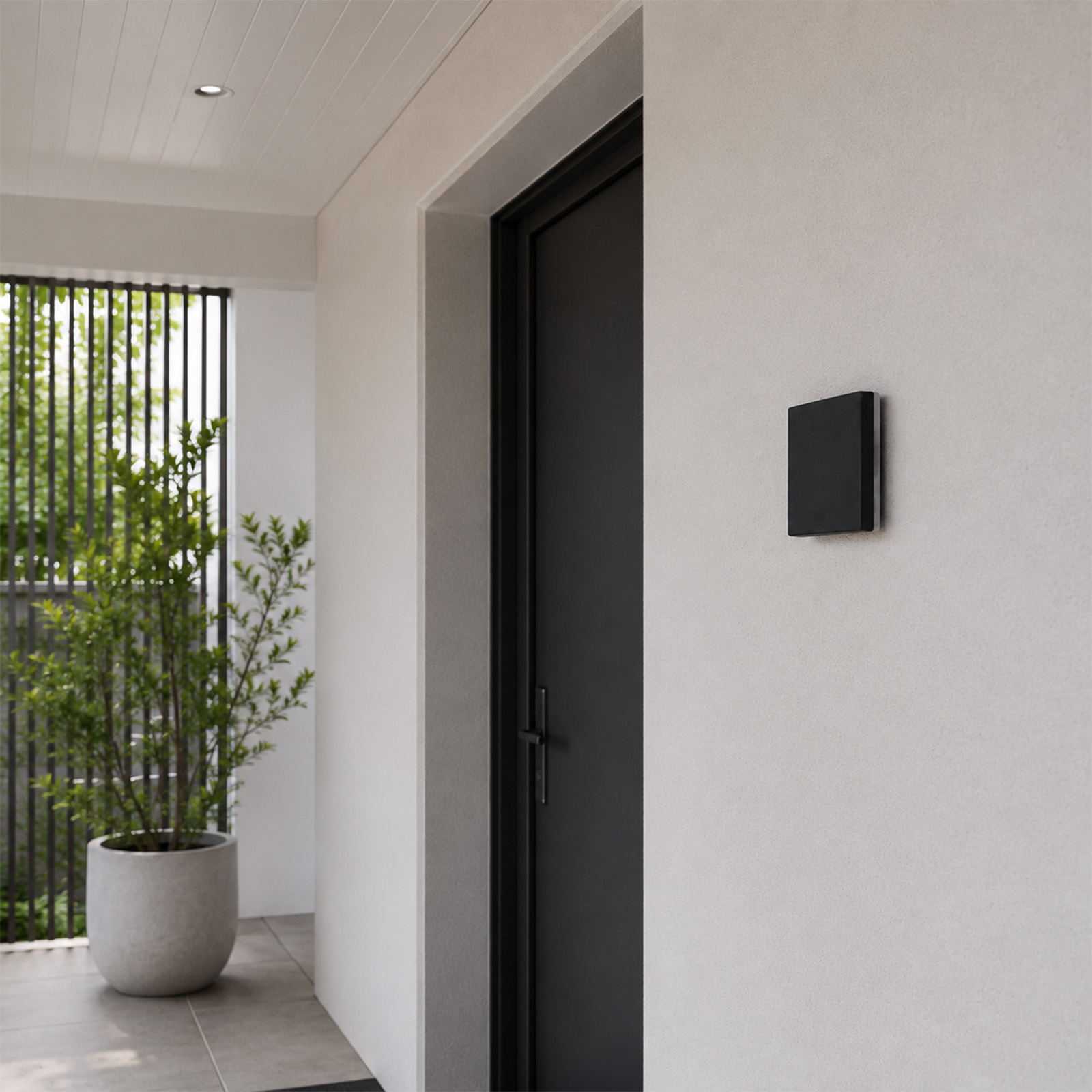Un timbre negro en una pared blanca, junto a una puerta negra.