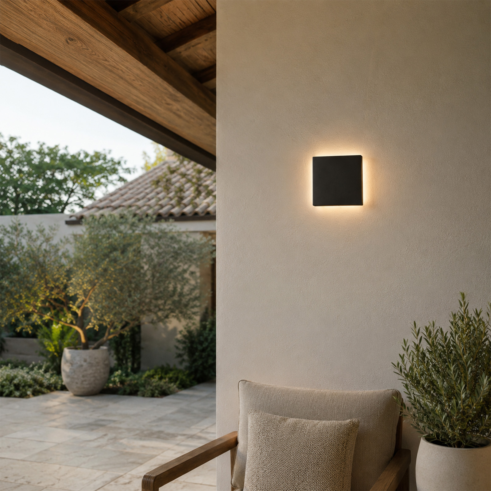 Una lámpara de pared cuadrada y negra brilla en una pared crema. Zona exterior.