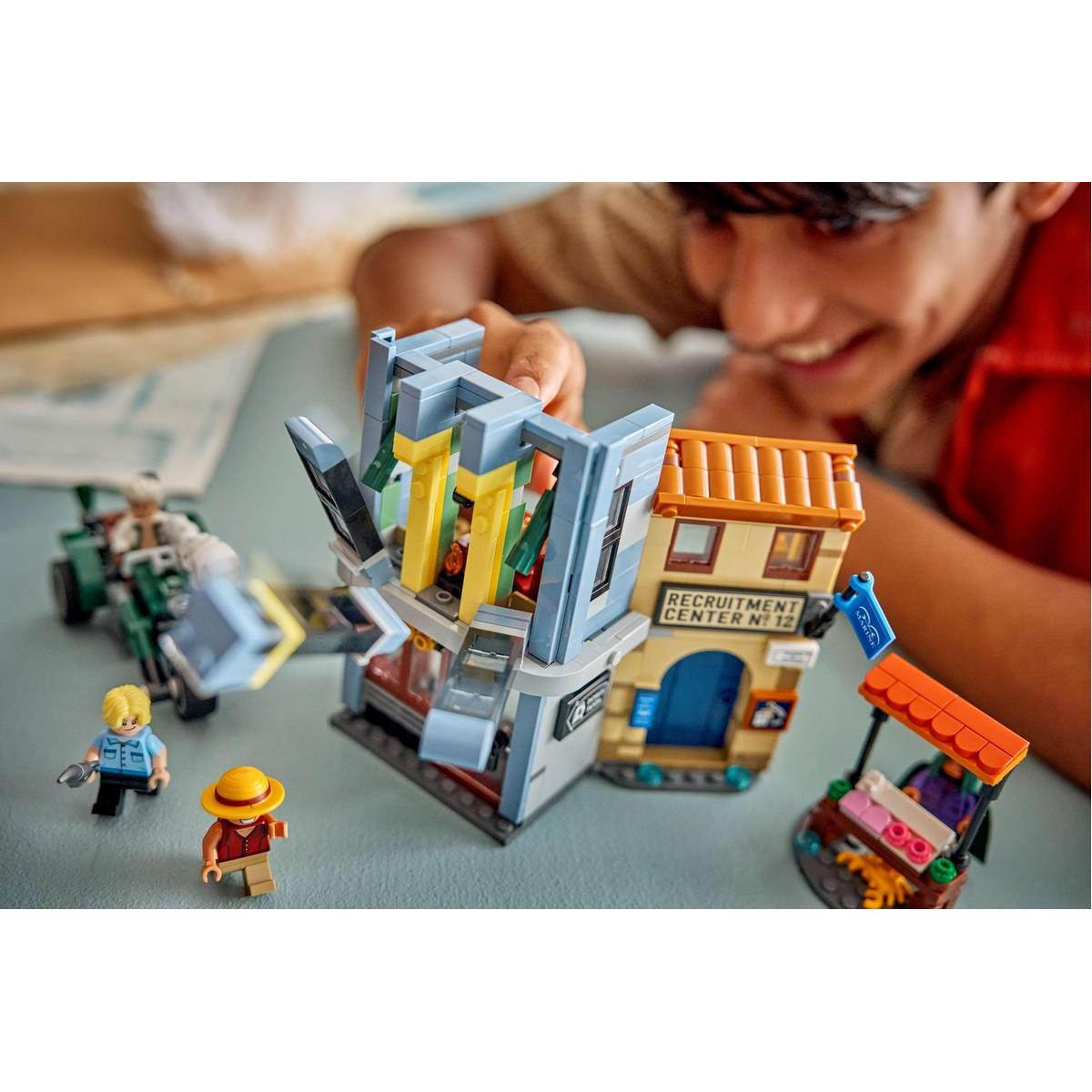 Ragazzo gioca con set Lego: centro reclutamento, veicolo e personaggi.