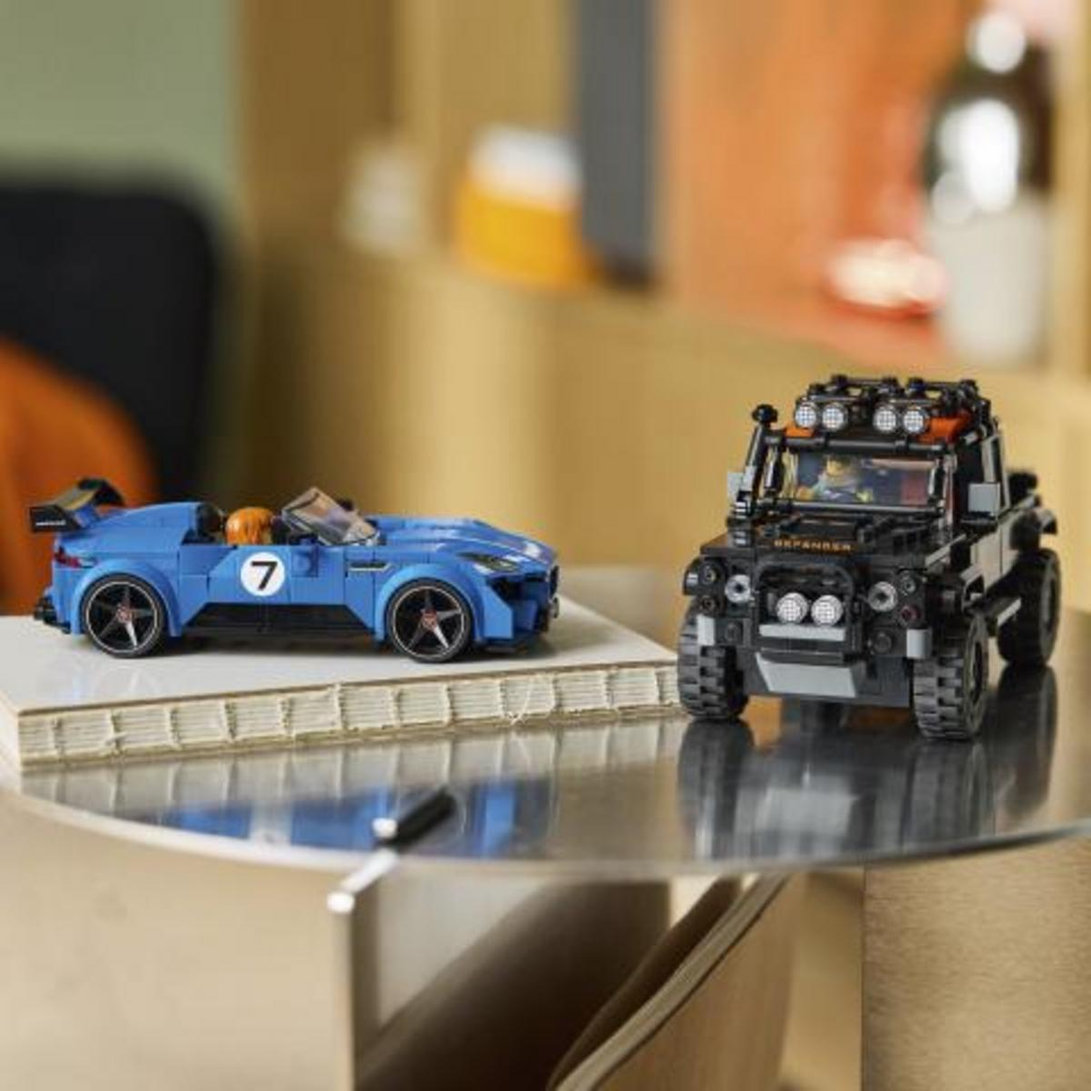 Una macchina sportiva Lego blu e un fuoristrada Lego nero sono uno accanto all'altro su un tavolo.