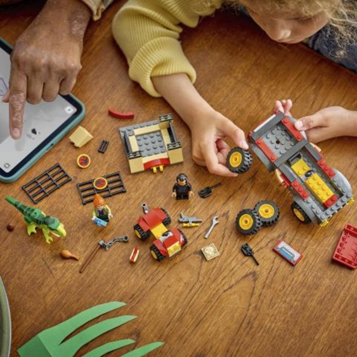 Bambini costruiscono giocattoli Lego, tra cui un dinosauro, auto e una figura, guidati da un tablet.