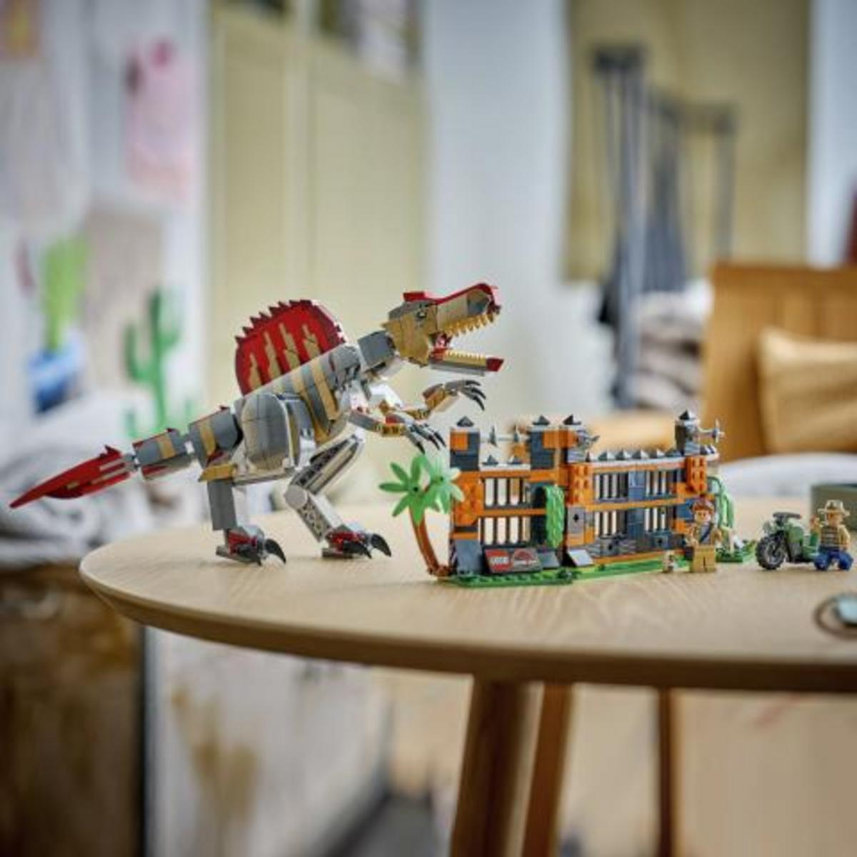 Giocattolo Lego Spinosaurus vicino a una struttura Lego Jurassic World, figure e moto.