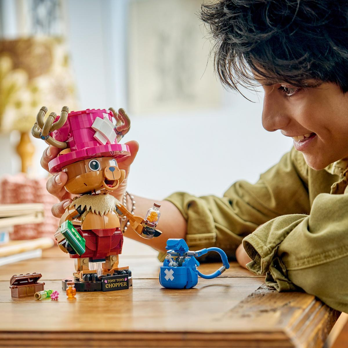 Un ragazzo gioca con una figura Lego di Tony Tony Chopper con cappello e medicine.