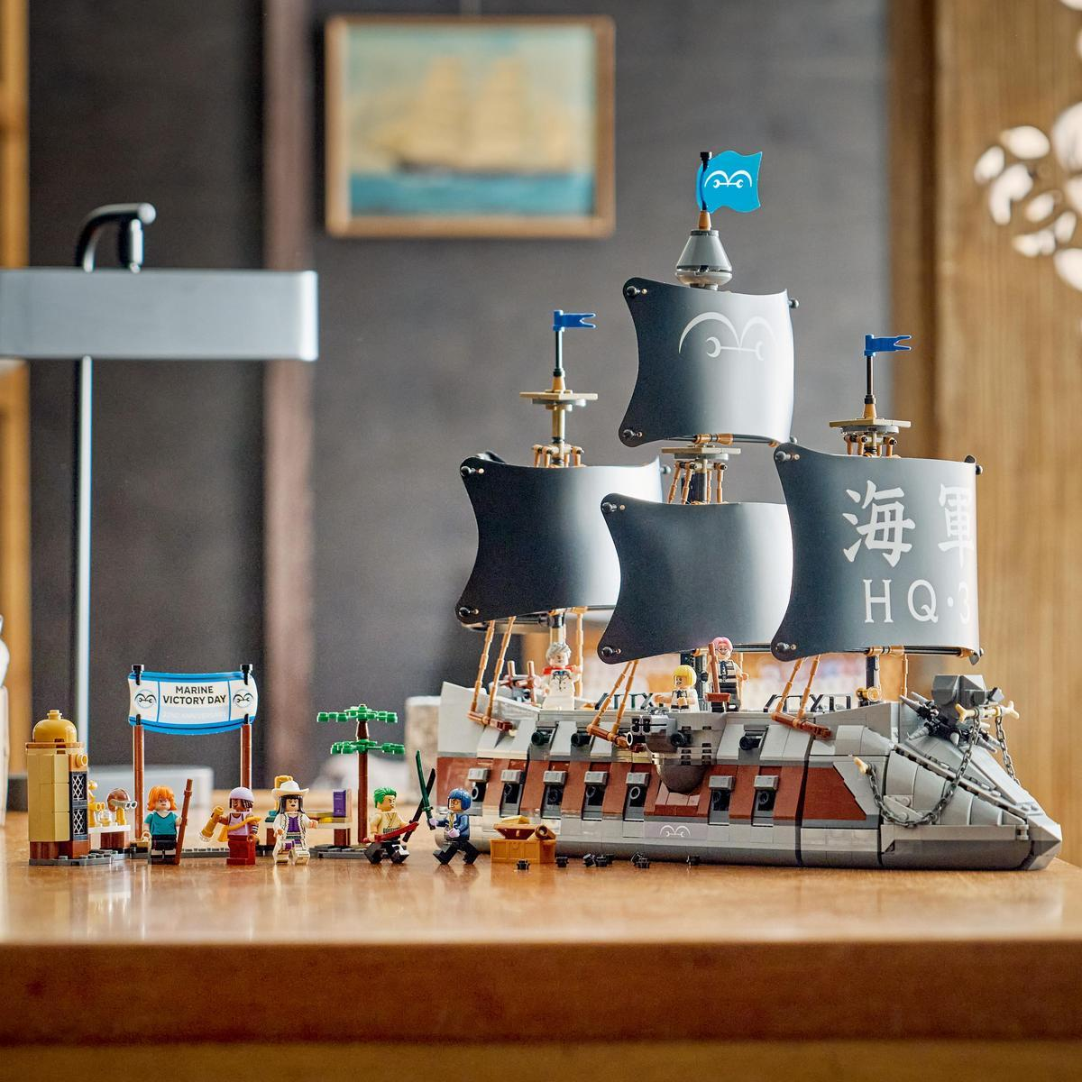 Un barco pirata de Lego con figuras se exhibe en una mesa de madera. Un cuadro cuelga en la pared.