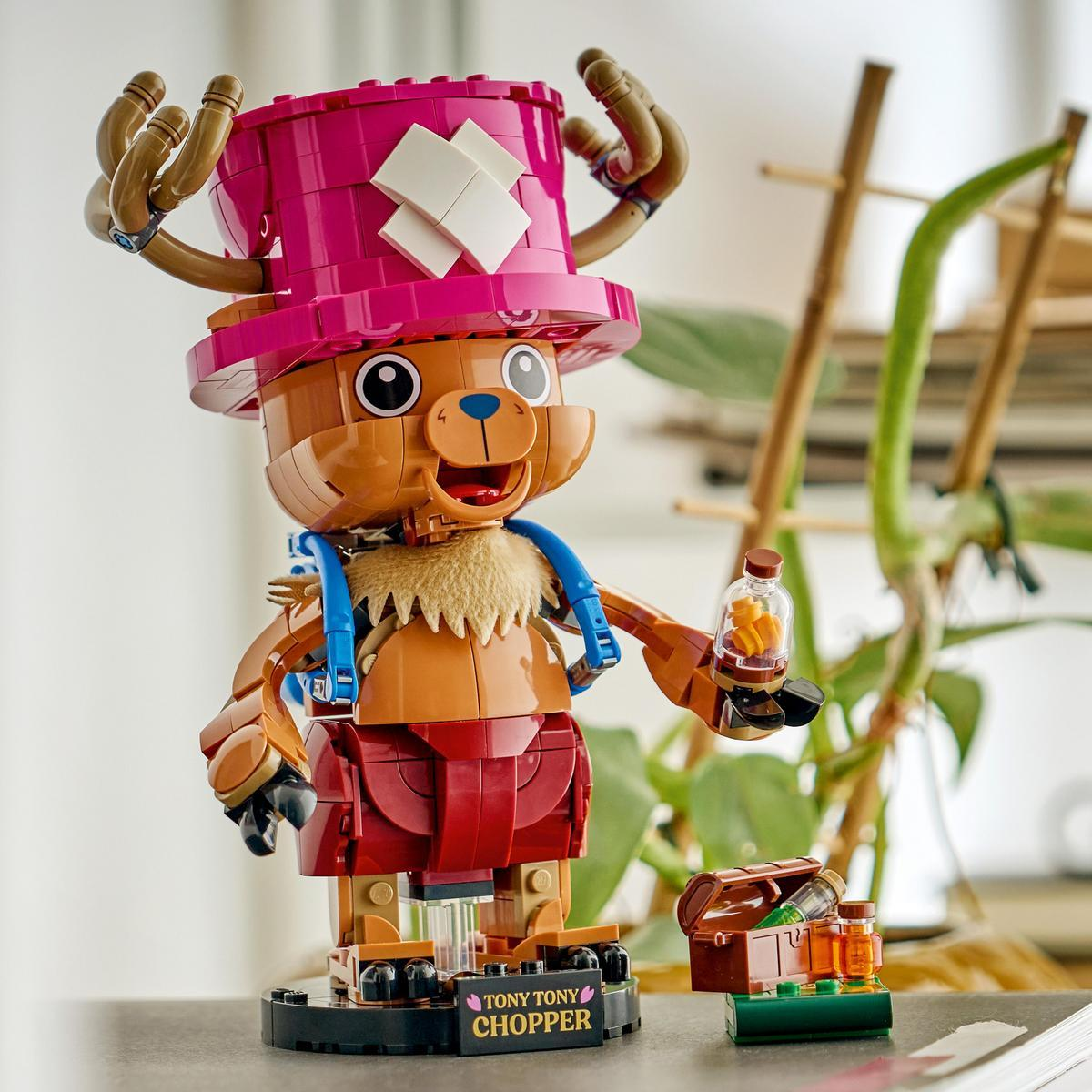 Un modello Lego di Tony Tony Chopper con cappello rosa, tiene una bottiglia con pillole arancioni.