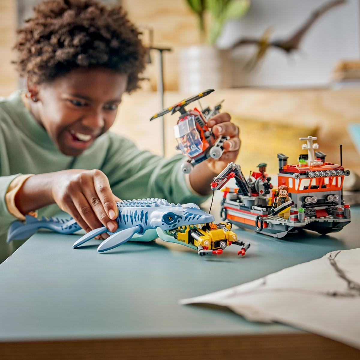 Un bambino gioca con giocattoli LEGO, tra cui una balena, una barca e un elicottero.