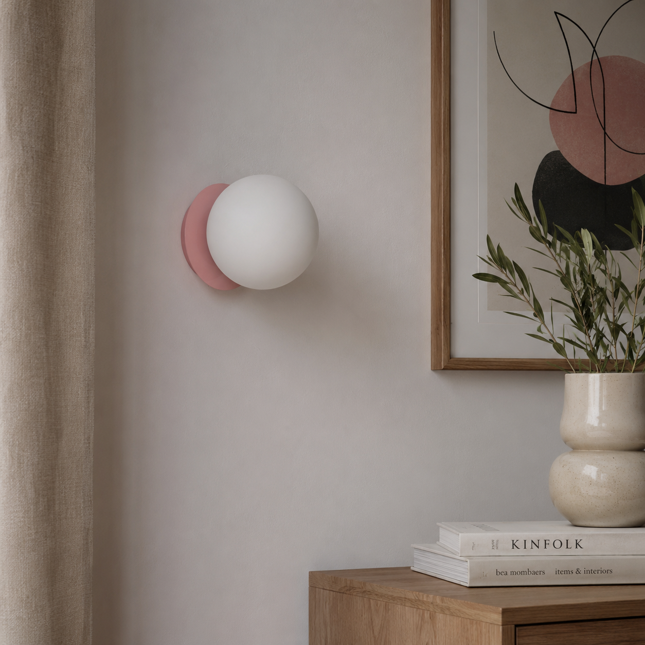 Una lámpara de pared esférica blanca con base rosa cuelga de la pared.