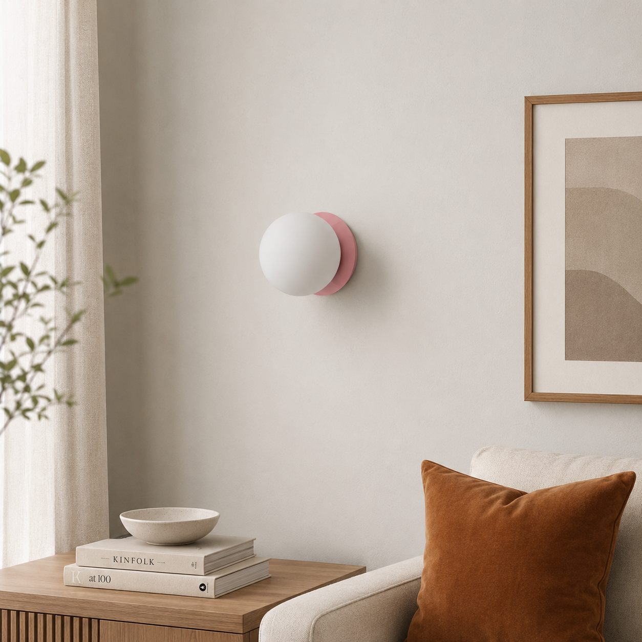 Una lámpara de pared de globo blanco con base rosa cuelga de una pared color crema.