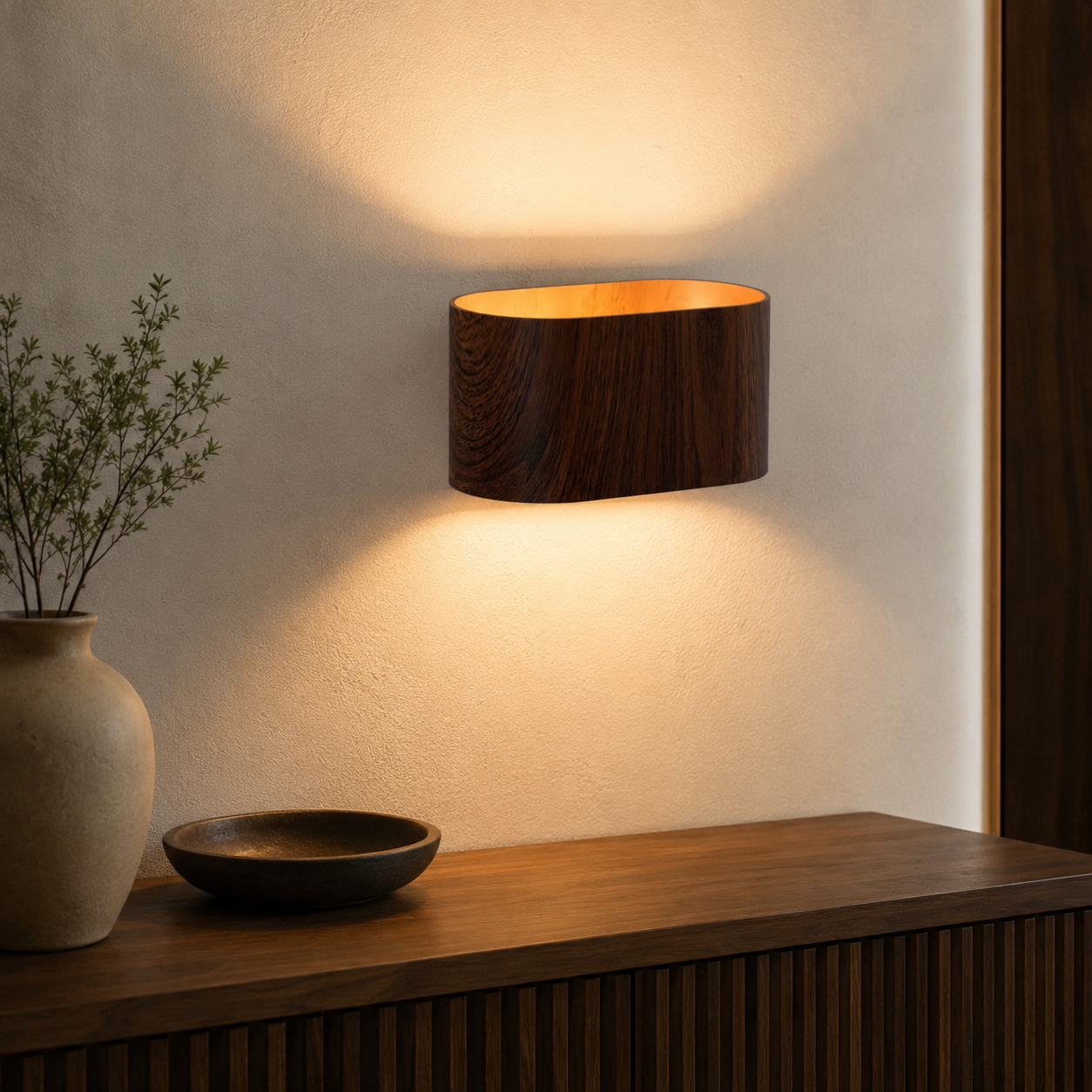 Un aplique de pared de madera oscura ilumina una pared sobre un mueble de madera.