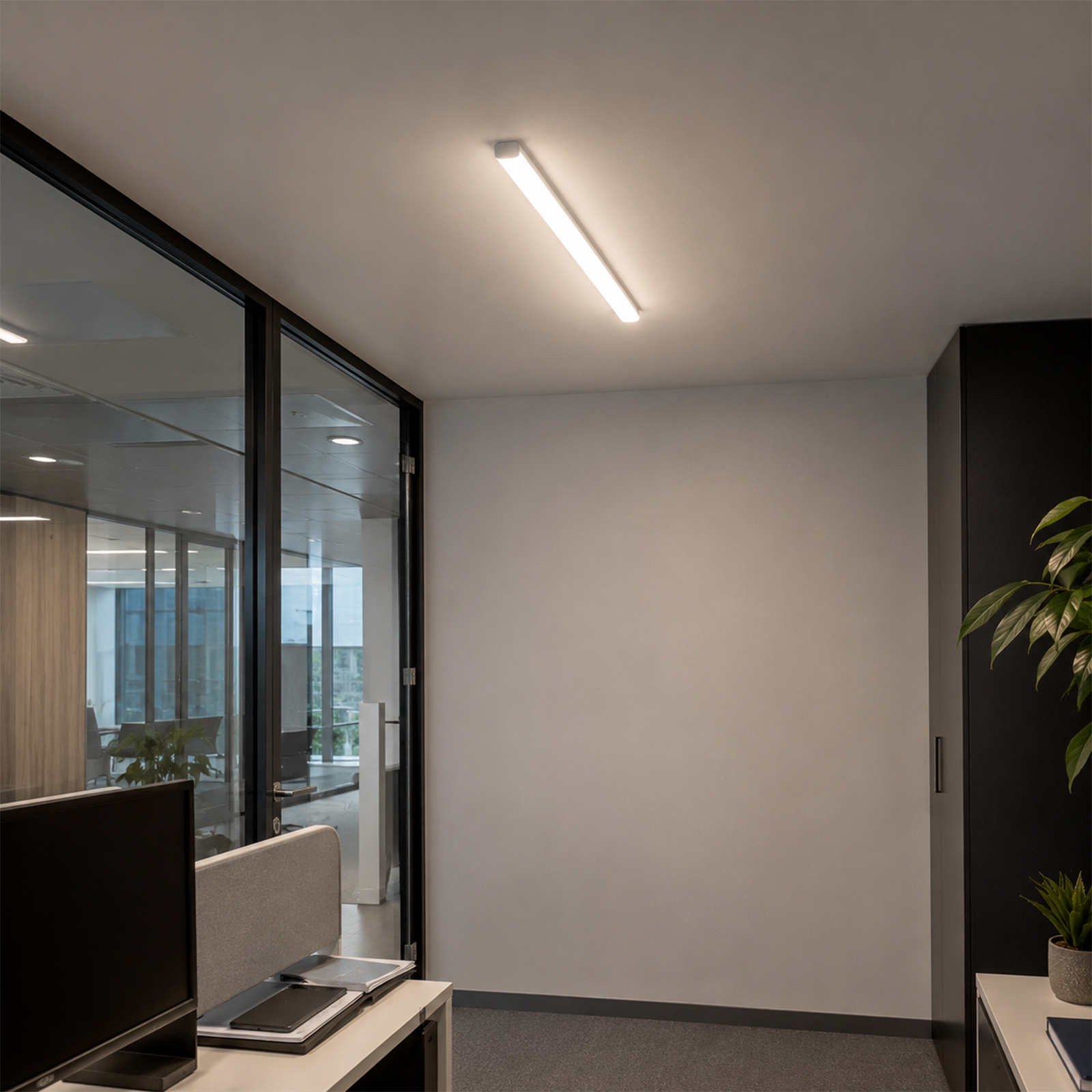 Un espacio de oficina moderno con paredes de cristal, un escritorio y una planta.