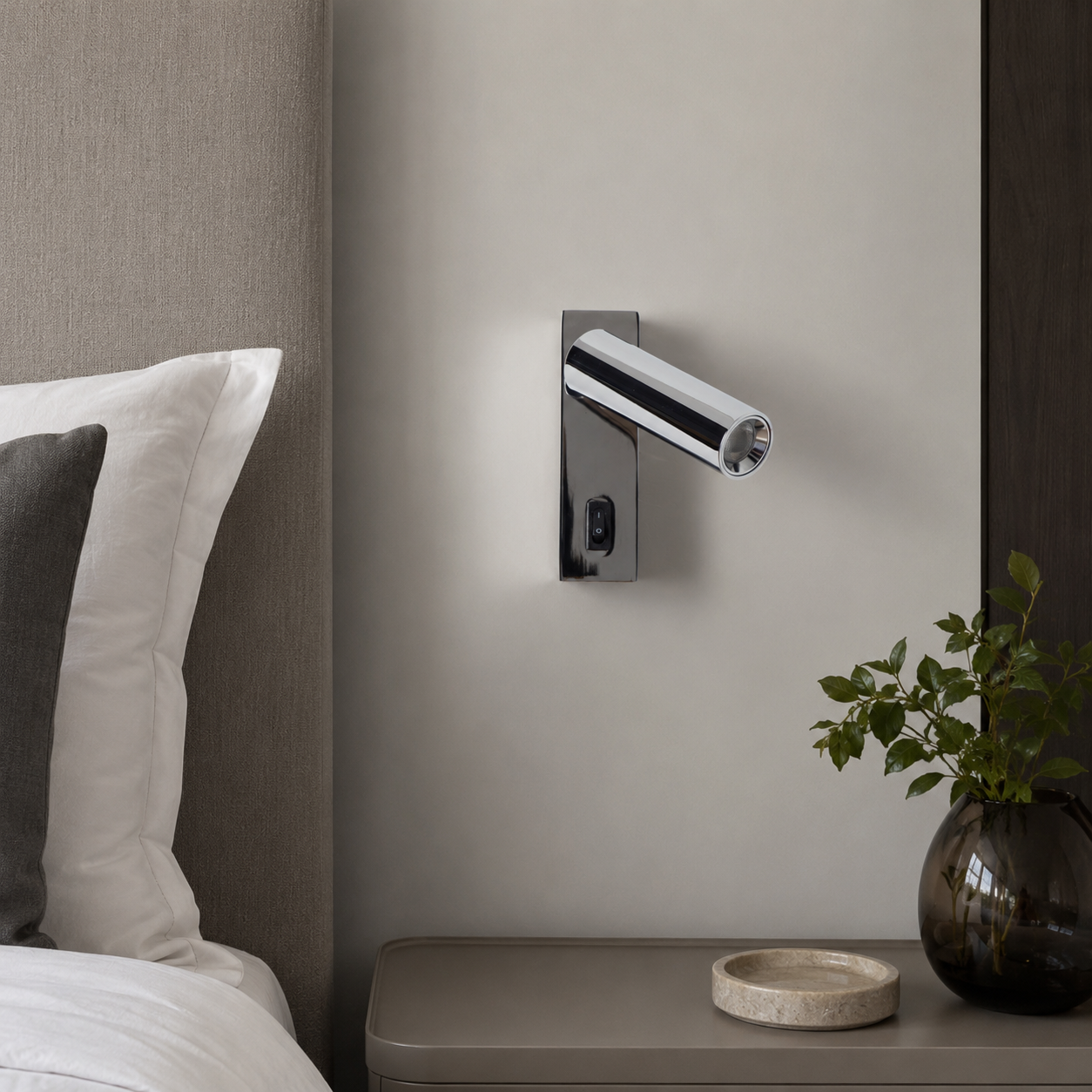 Un aplique de pared moderno con interruptor sobre una pared gris claro encima de una mesita.