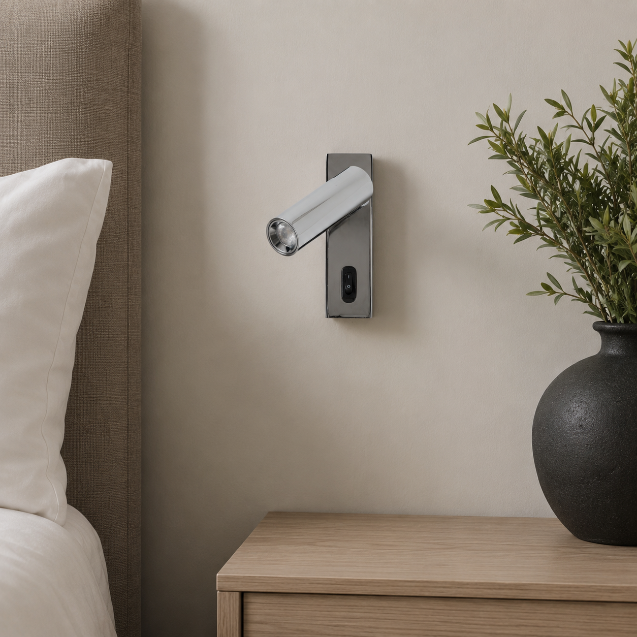 Un aplique de pared orientable sobre una mesita de noche junto a una cama.
