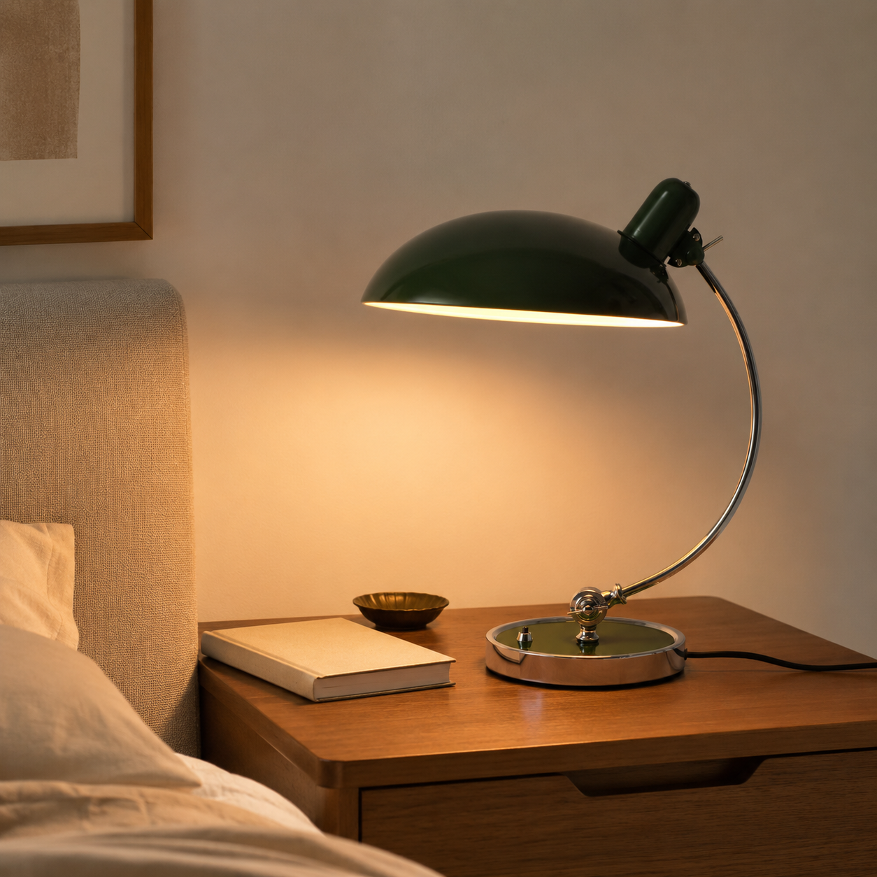 Una lámpara de escritorio verde ilumina una mesita de noche junto a una cama.